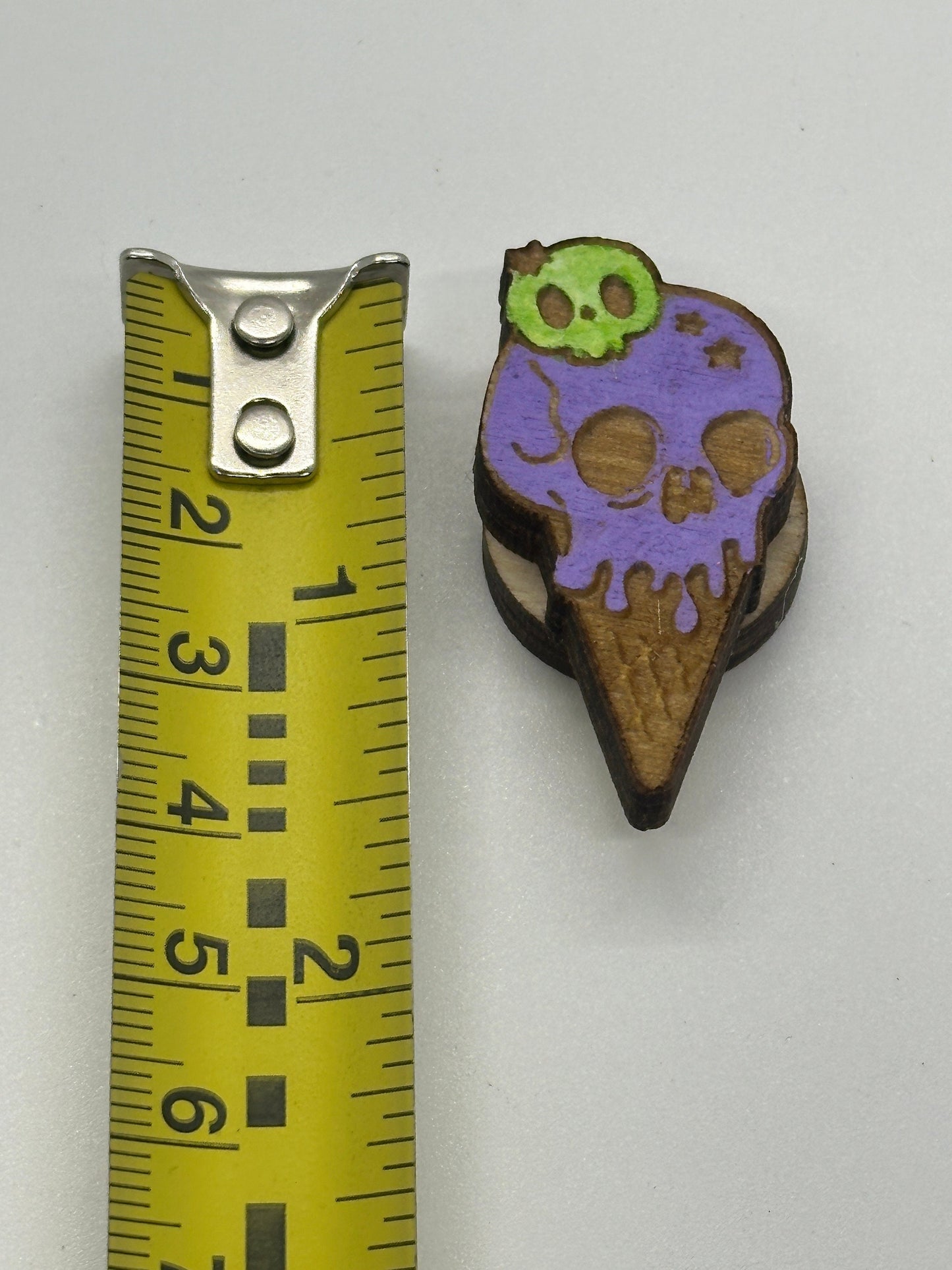 Purple and brown ice cream cone-shaped object next to a ruler on a white background
