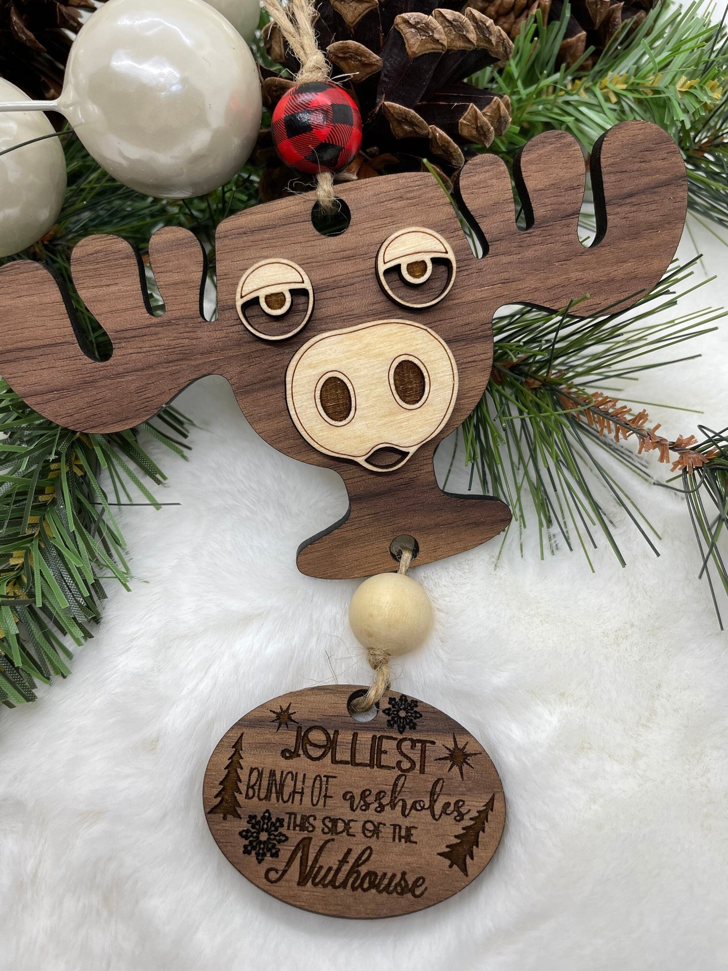 Wooden moose ornament with humorous text on a snowy background