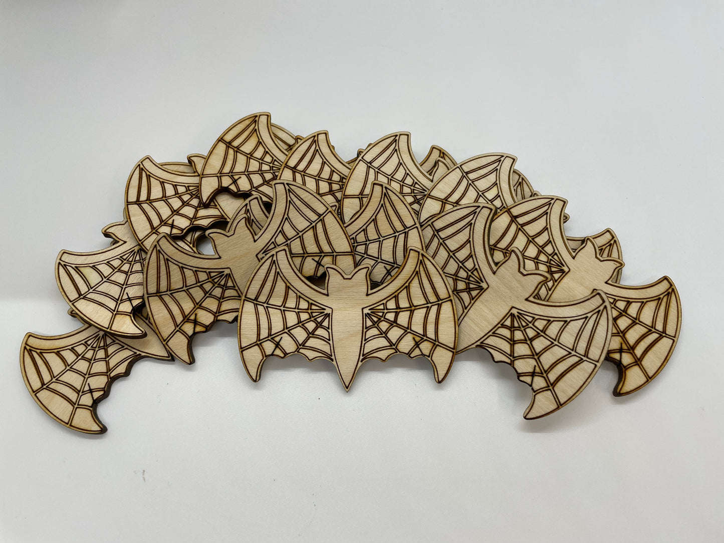 Wooden cutout shapes of bats and webs on a white background