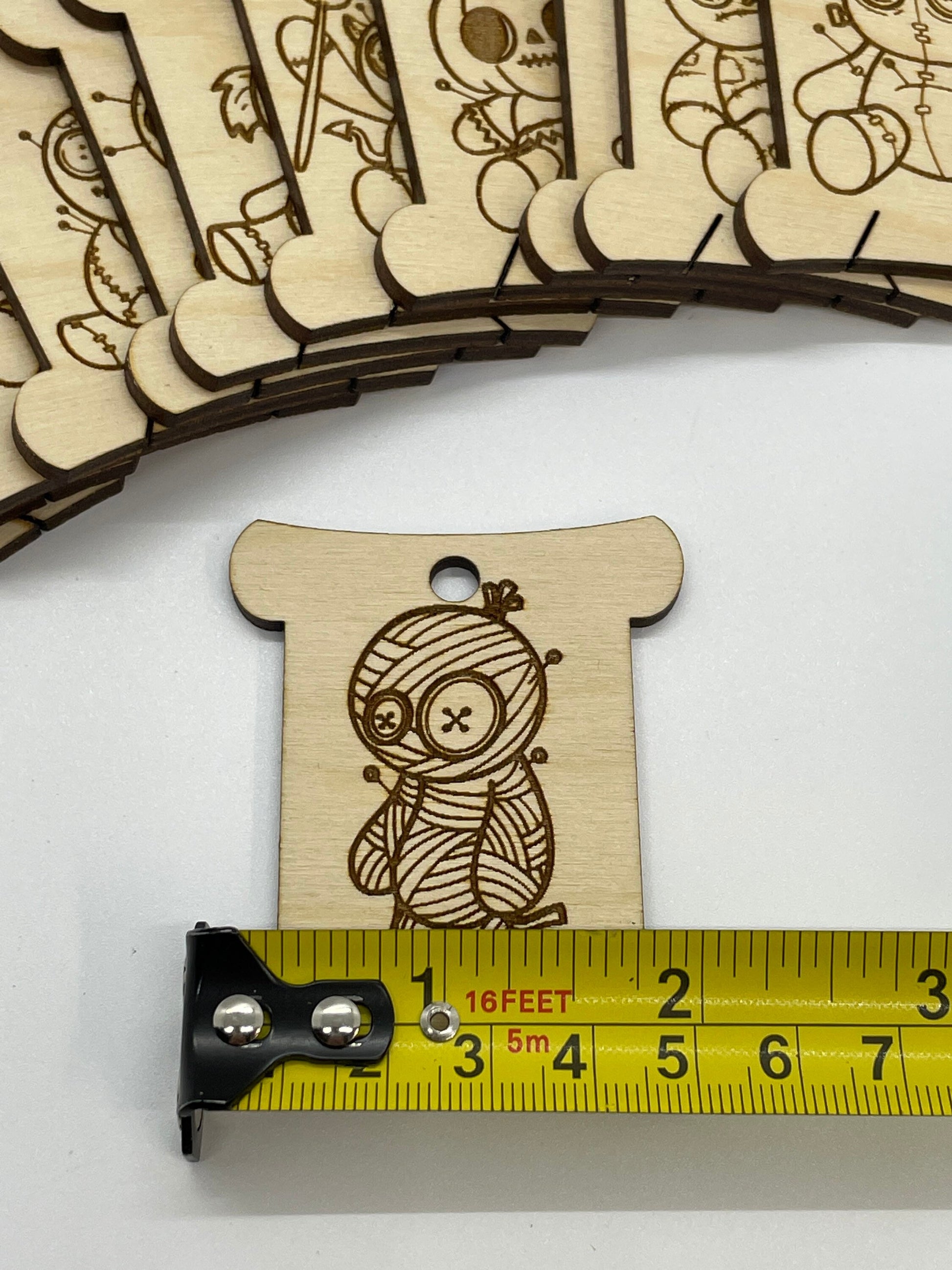 Wooden mummy design next to a measuring tape on a white background
