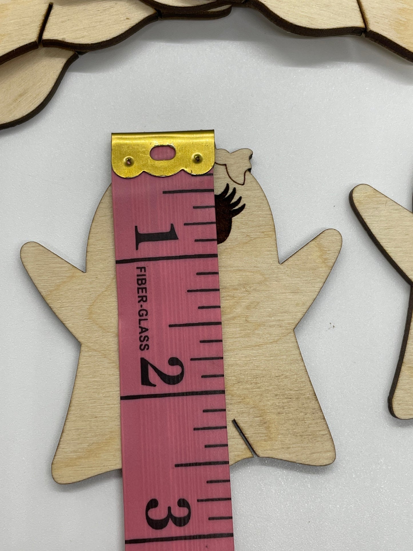 Wooden cutout of a hand with a pink measuring tape showing 2.5 inches
