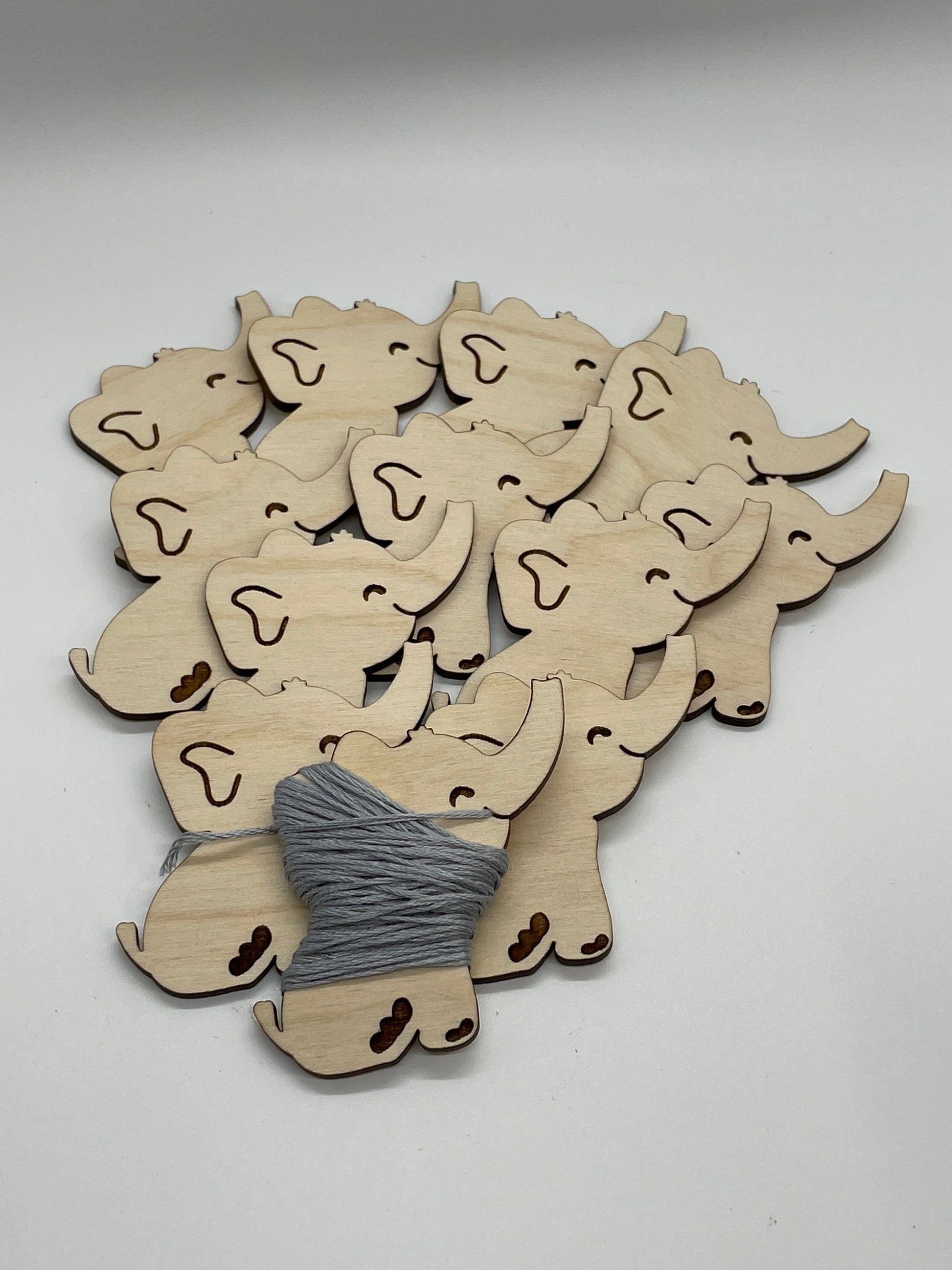 Wooden elephant shapes with a spool of thread on a white background