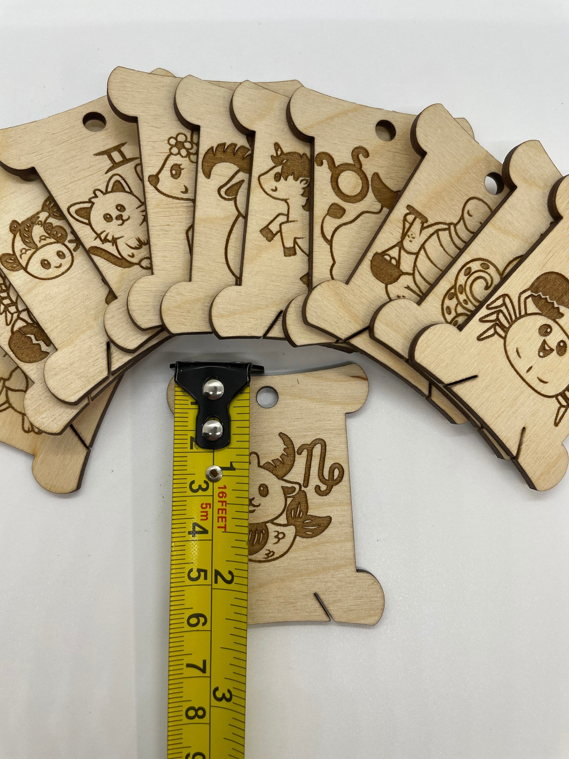 Wooden bobbins with animal illustrations and a measuring tape for scale on a white background