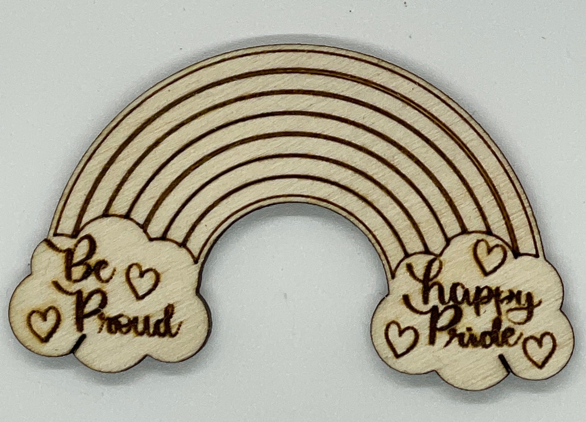 Wooden rainbow decoration with 'Be Proud' and 'Happy Bride' text on clouds against a white background