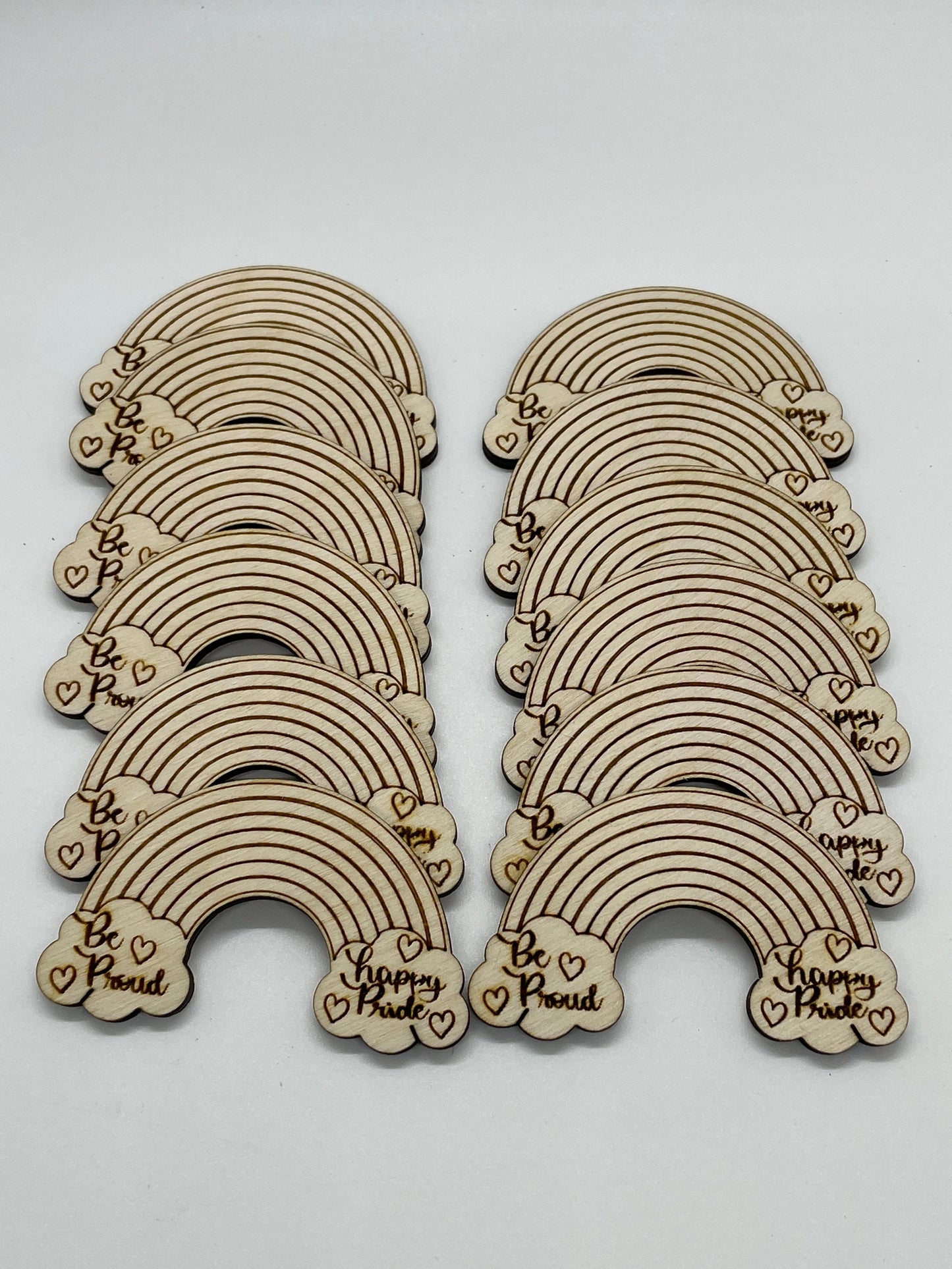 Set of wooden rainbow-shaped decorations with engraved text on a white background
