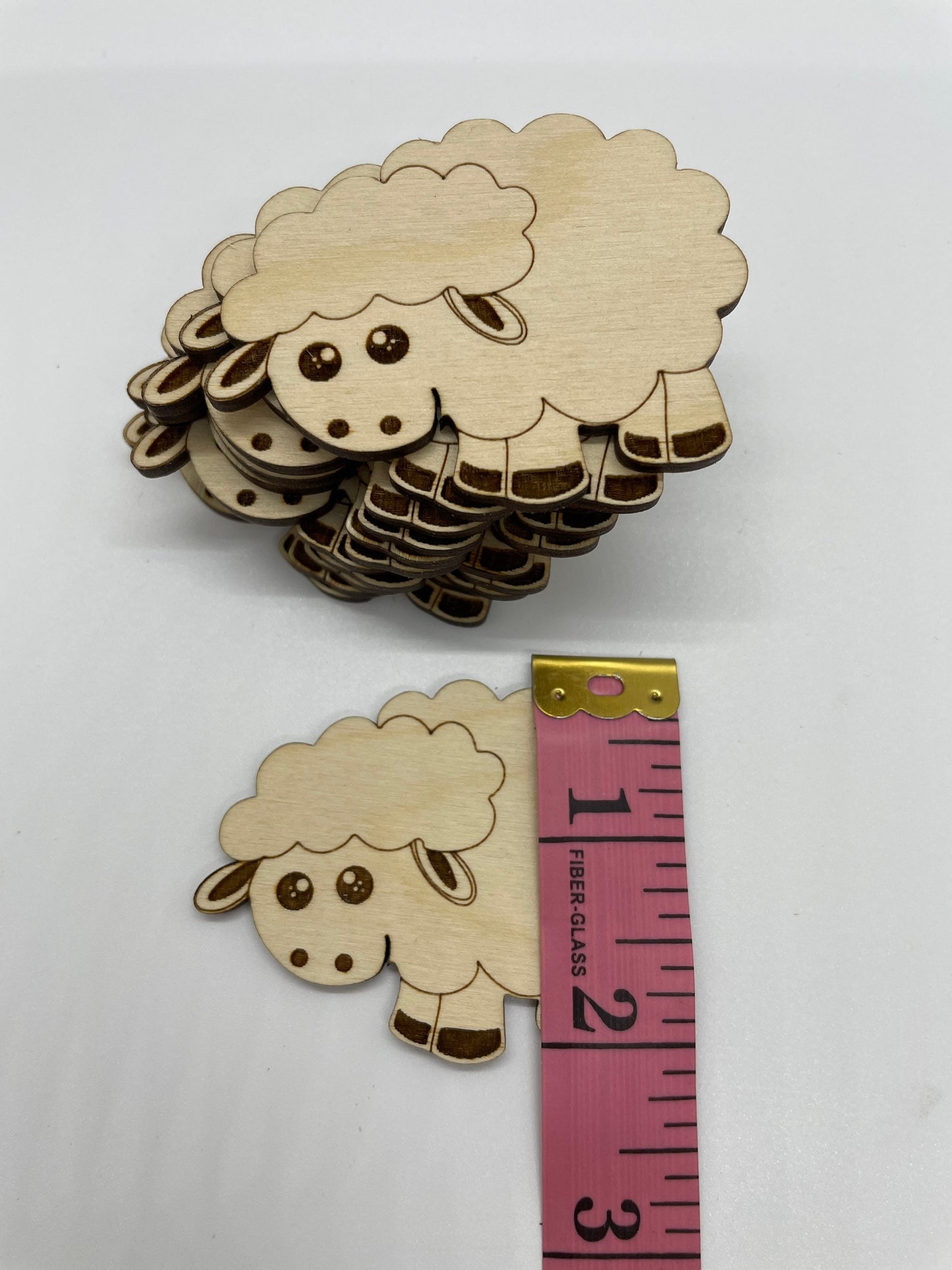 Wooden sheep cutout with a measuring tape for scale on a white background