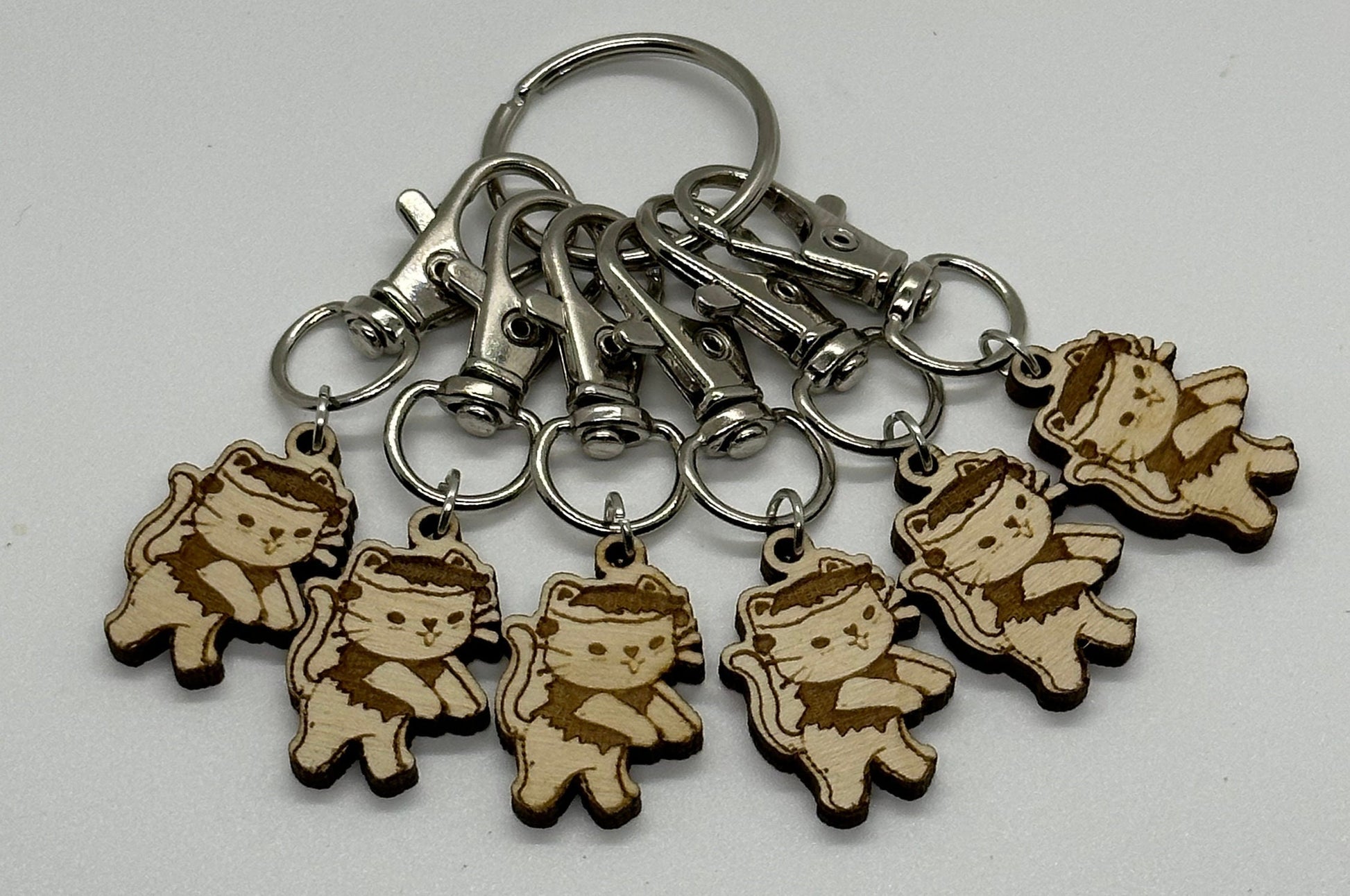 Set of keychains with wooden charms shaped like cats in costumes on a white background