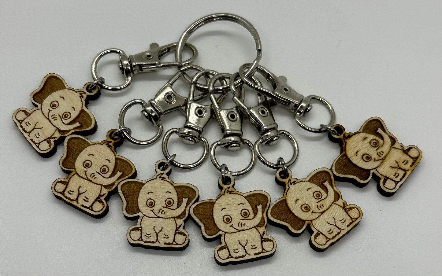 Set of elephant-shaped keychains on a gray background