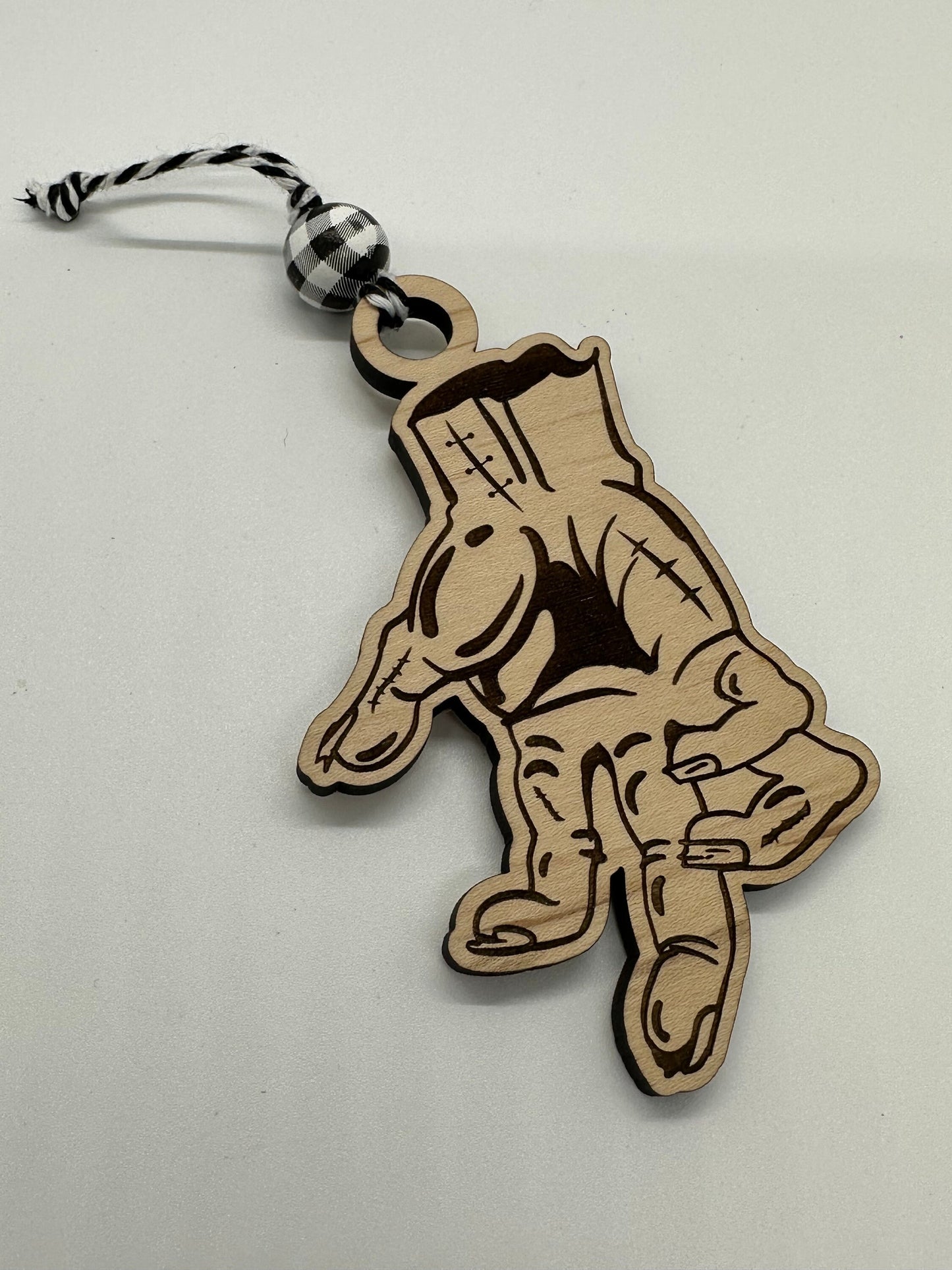 Wooden keychain with a design of a hand on a light gray background.