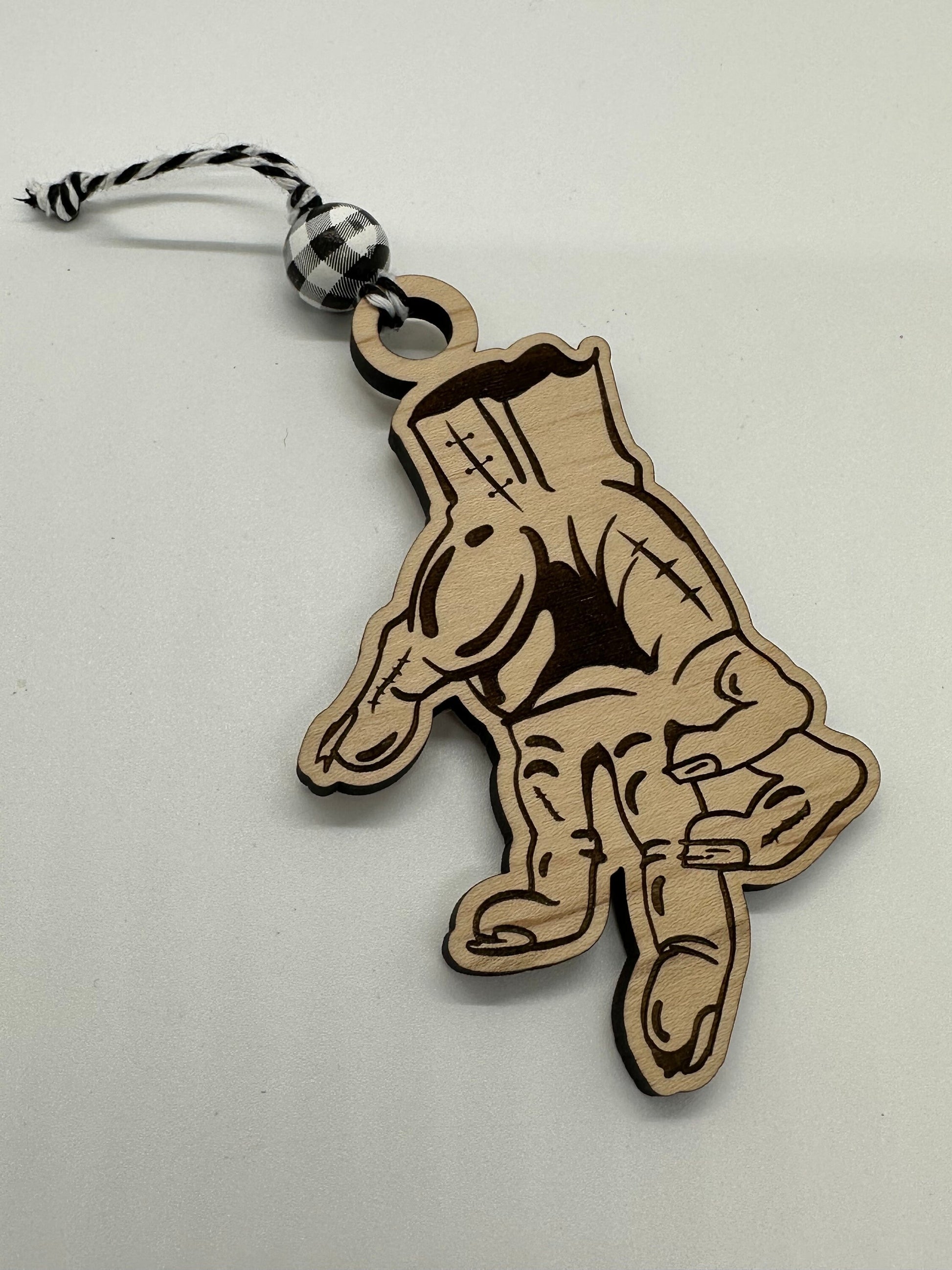 Wooden keychain with a design of a hand on a light gray background.