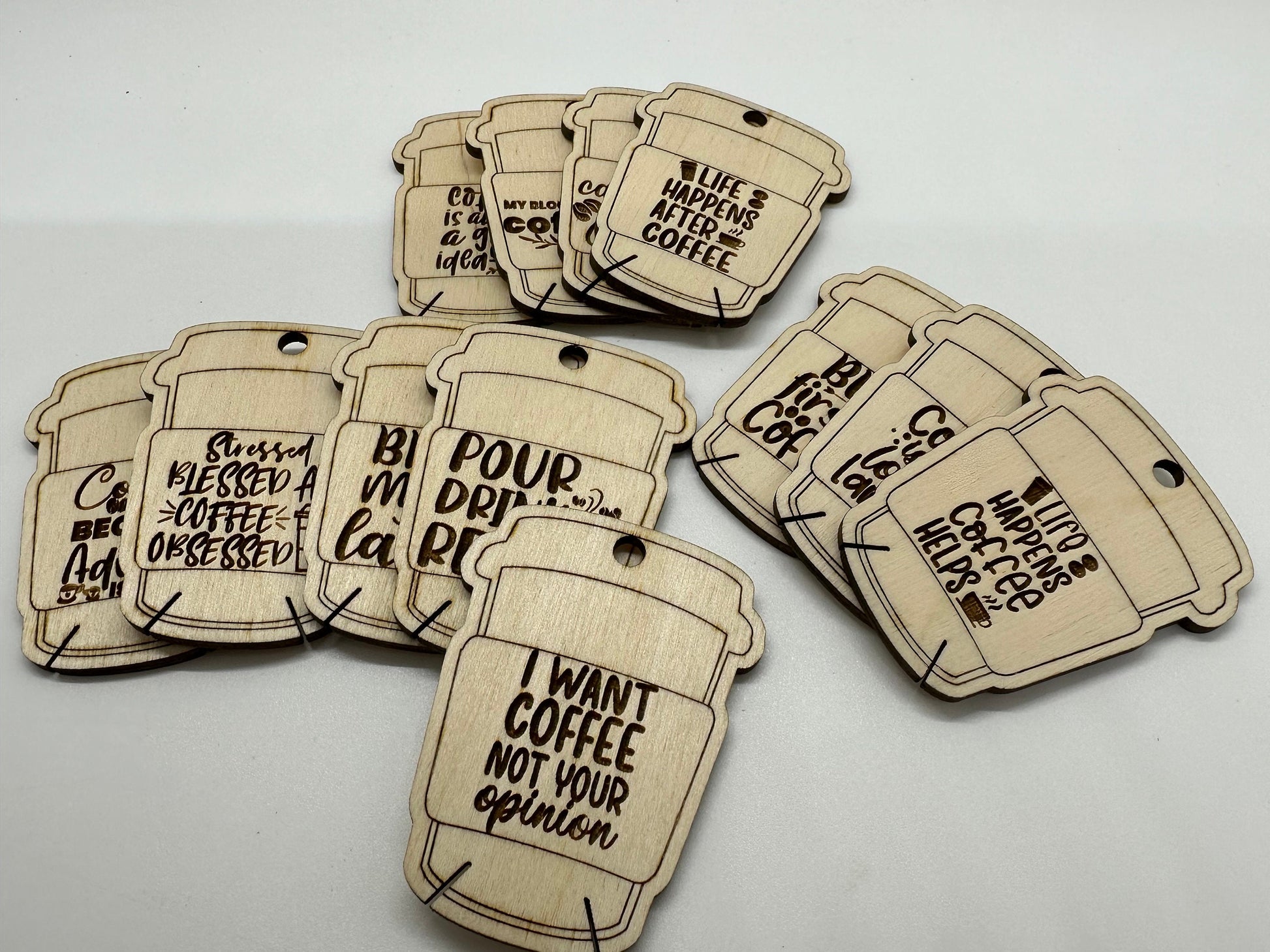 Wooden coffee-themed bobbins with humorous sayings on a white background