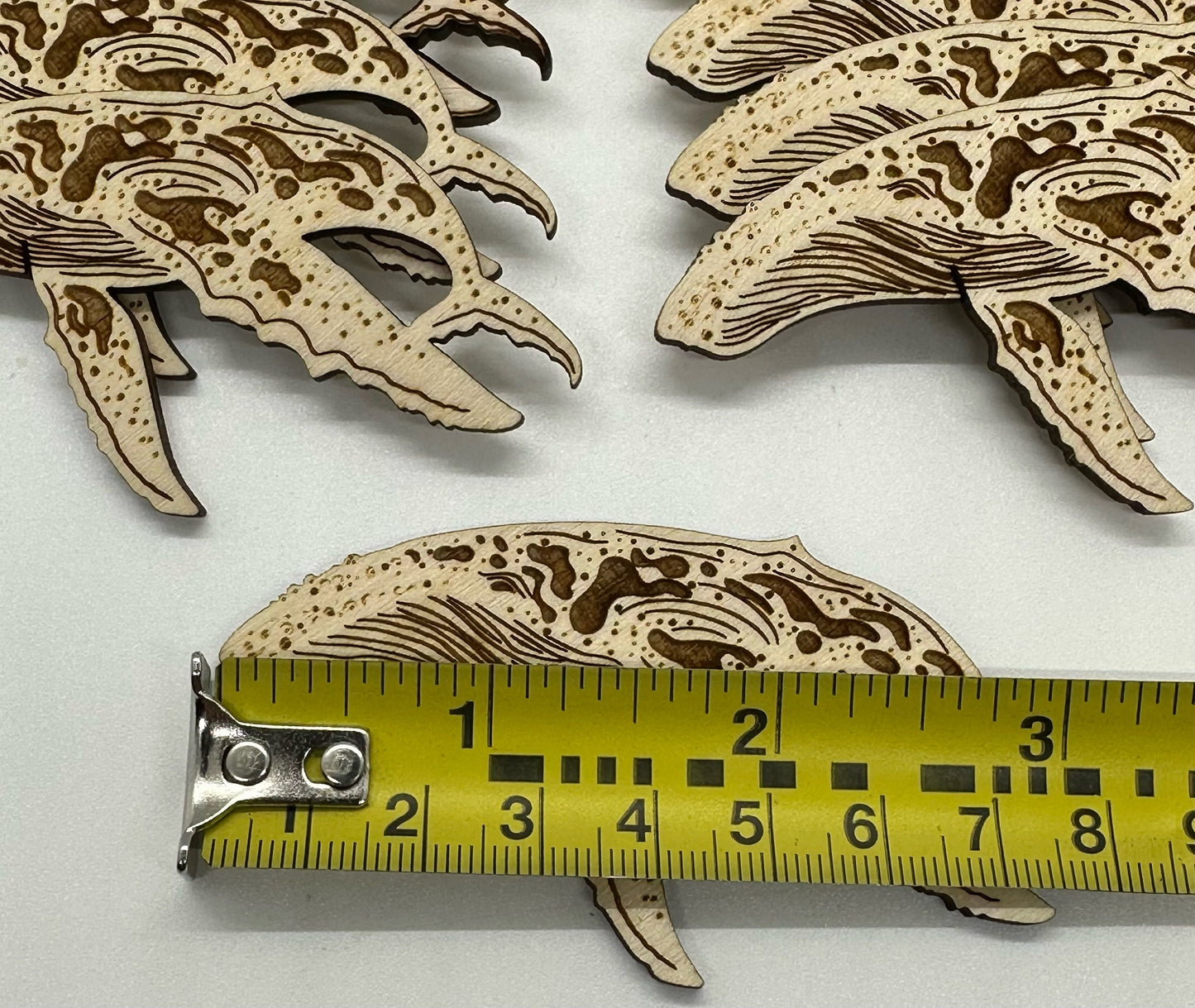 Wooden humpback whale cutouts on a white background with a ruler