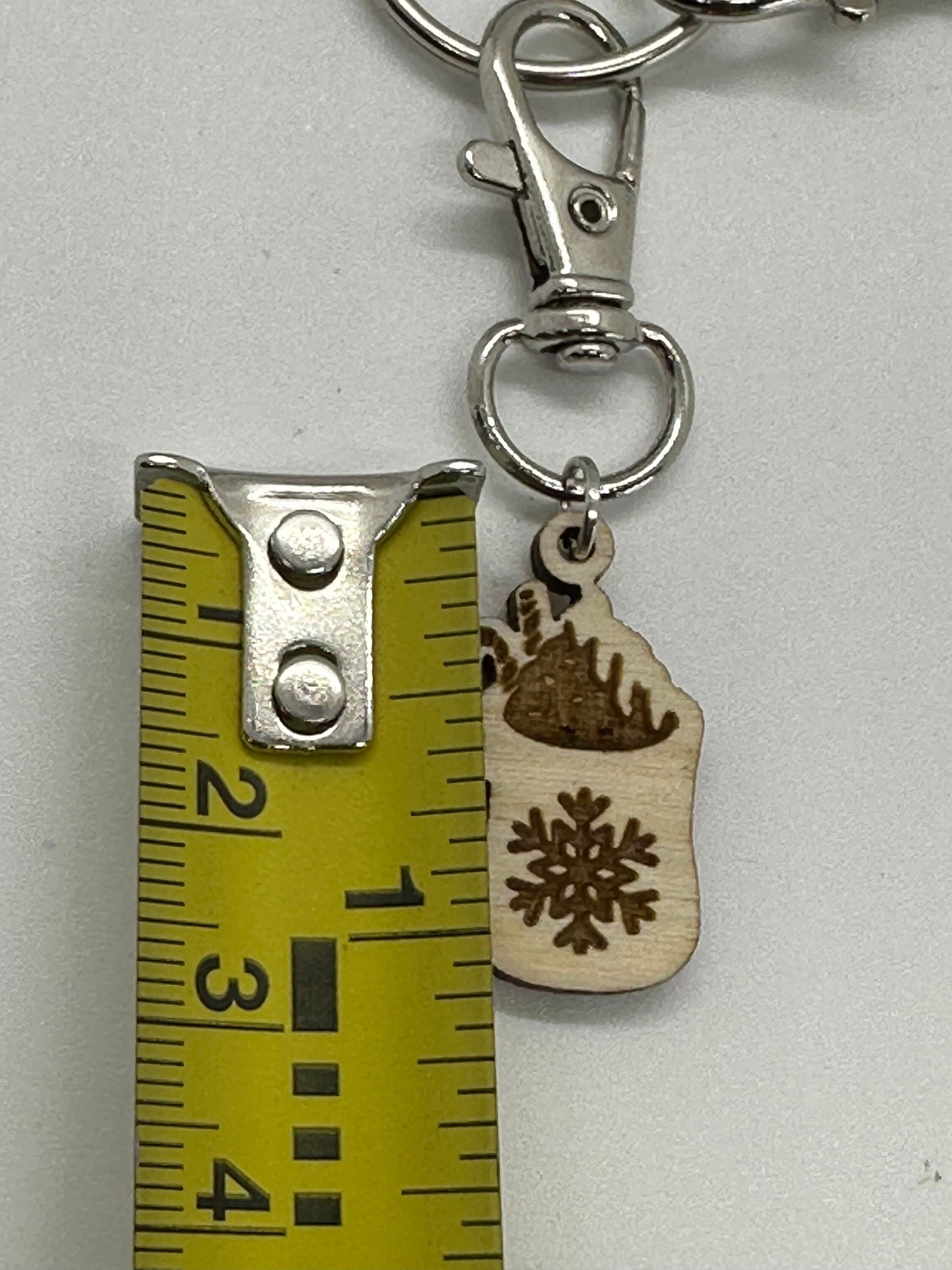 Keychain with wooden mug-shaped charm and snowflake design, next to a ruler for scale.