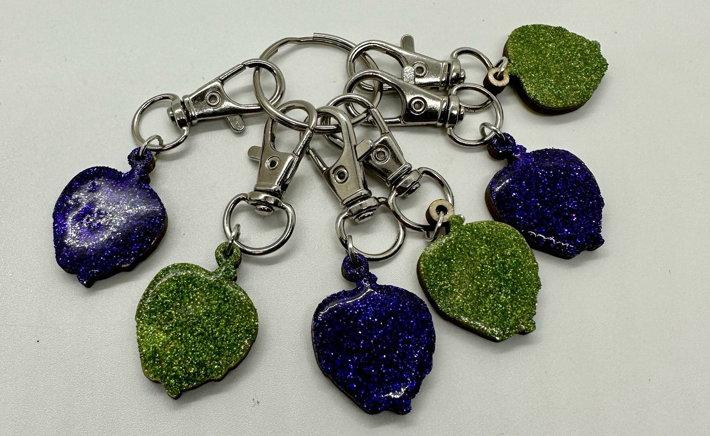 Set of keychains with green and blue glittery heart-shaped charms on a white background