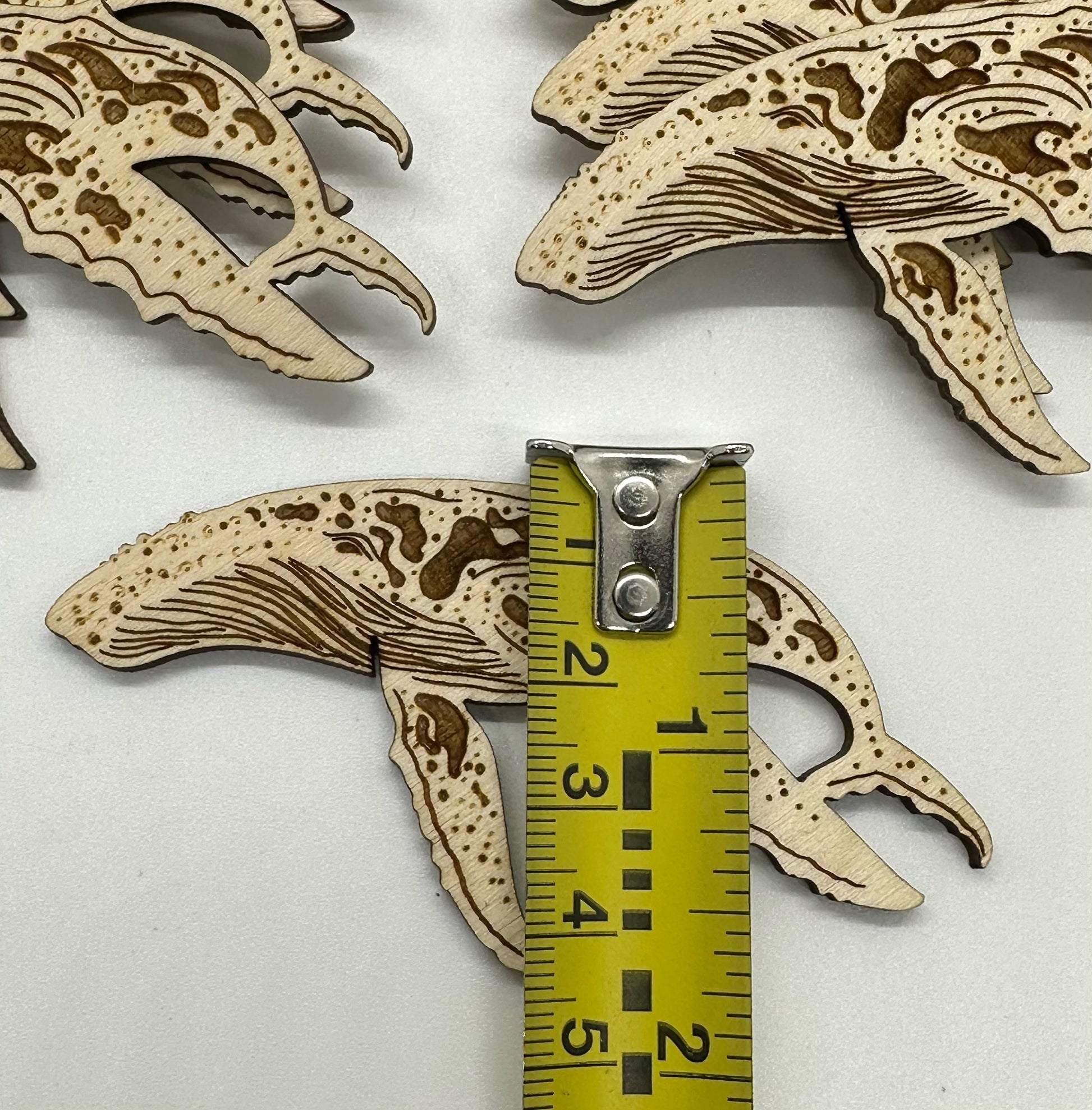 Wooden humpback whale cutouts on a white background with a ruler