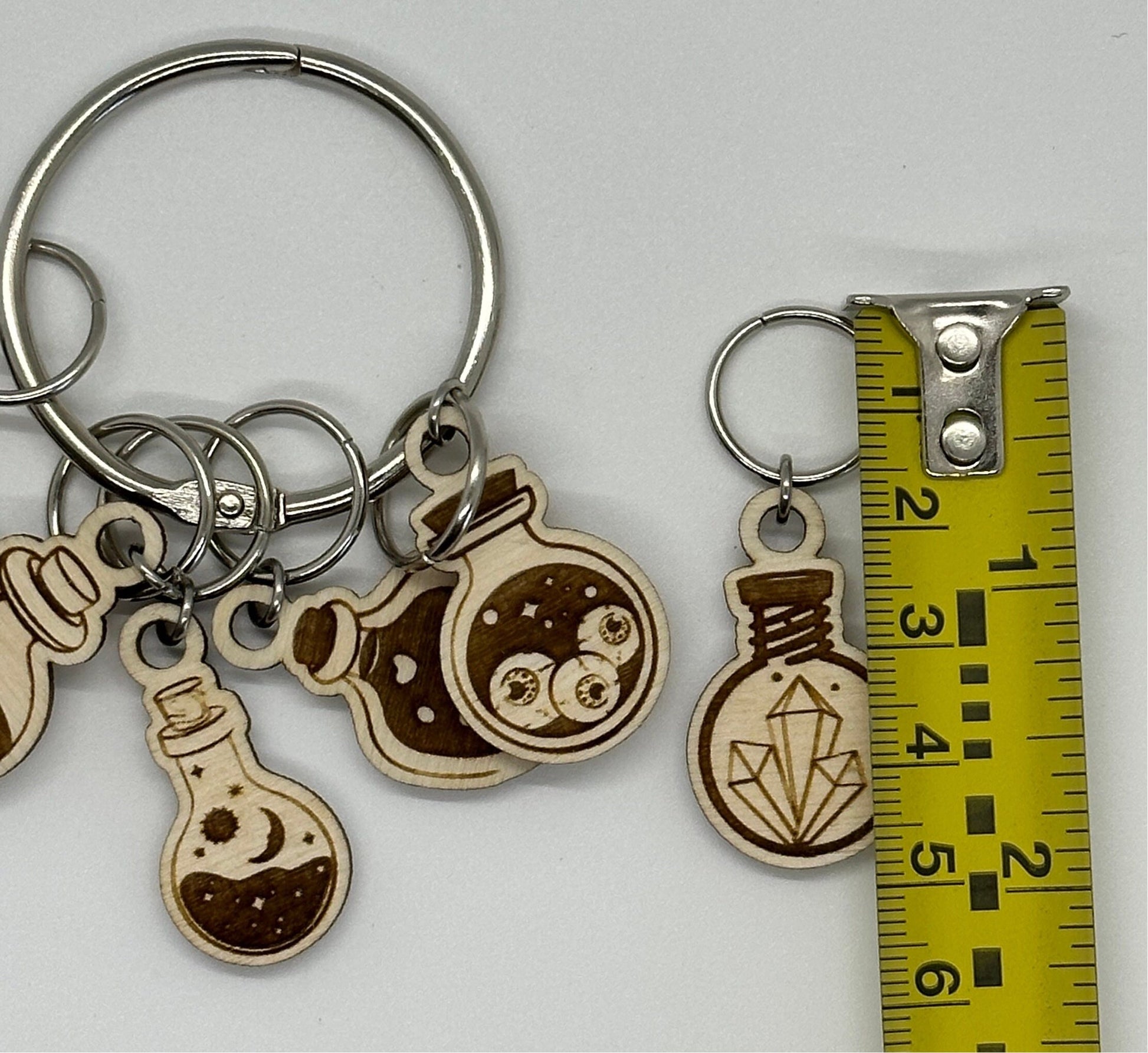 Keychain with wooden potion bottle charms next to a measuring tape for scale on a white background