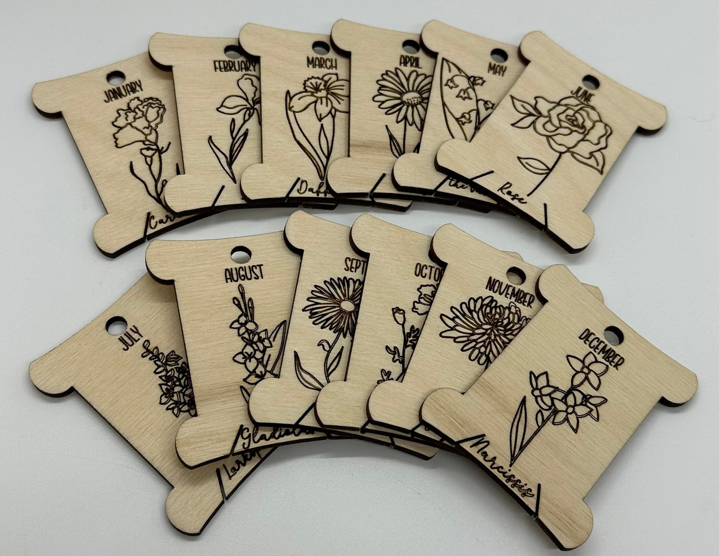 Wooden bobbins with floral designs and months of the year text on a white background