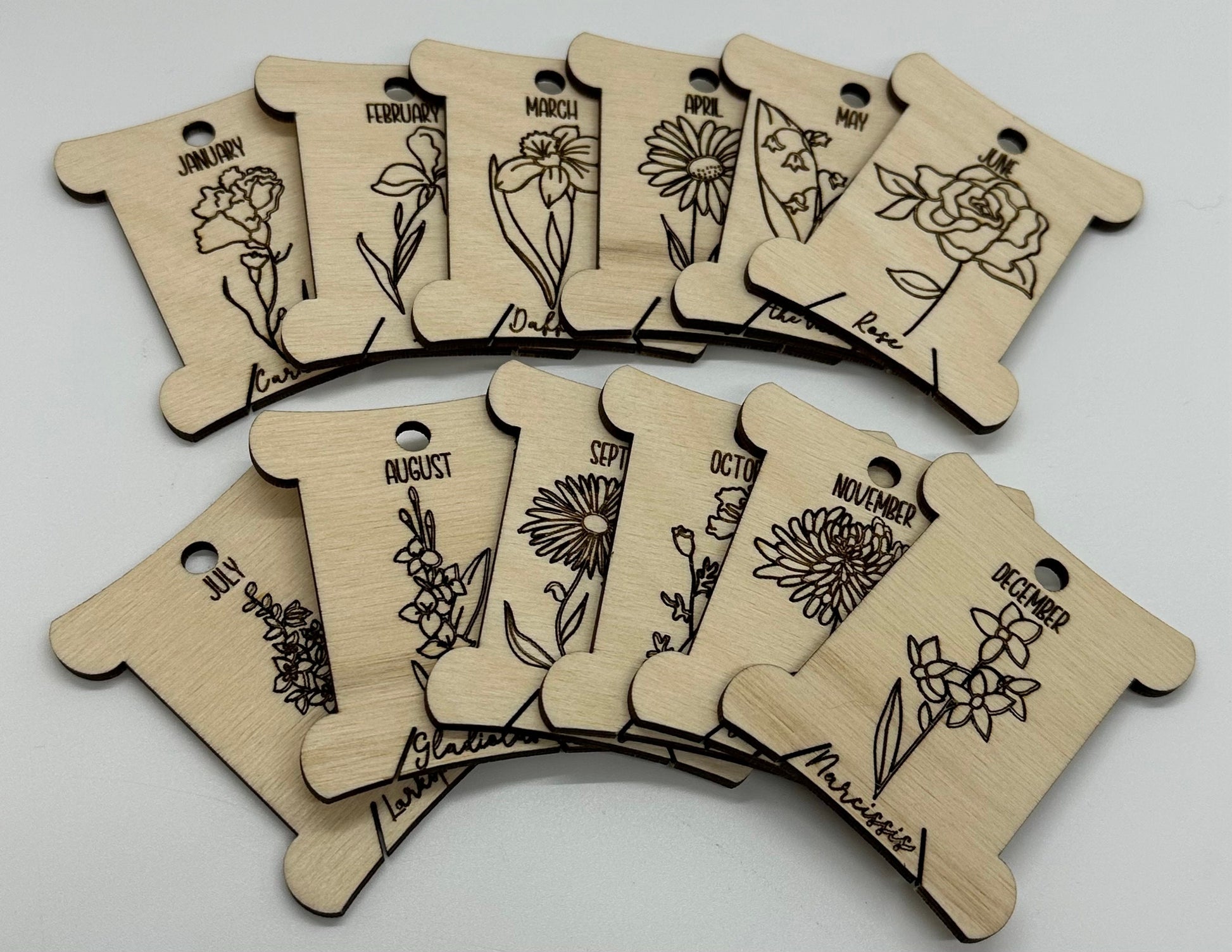 Wooden bobbins with floral designs and months of the year text on a white background