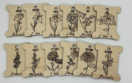 Wooden bobbins with floral designs and months' names on a white background