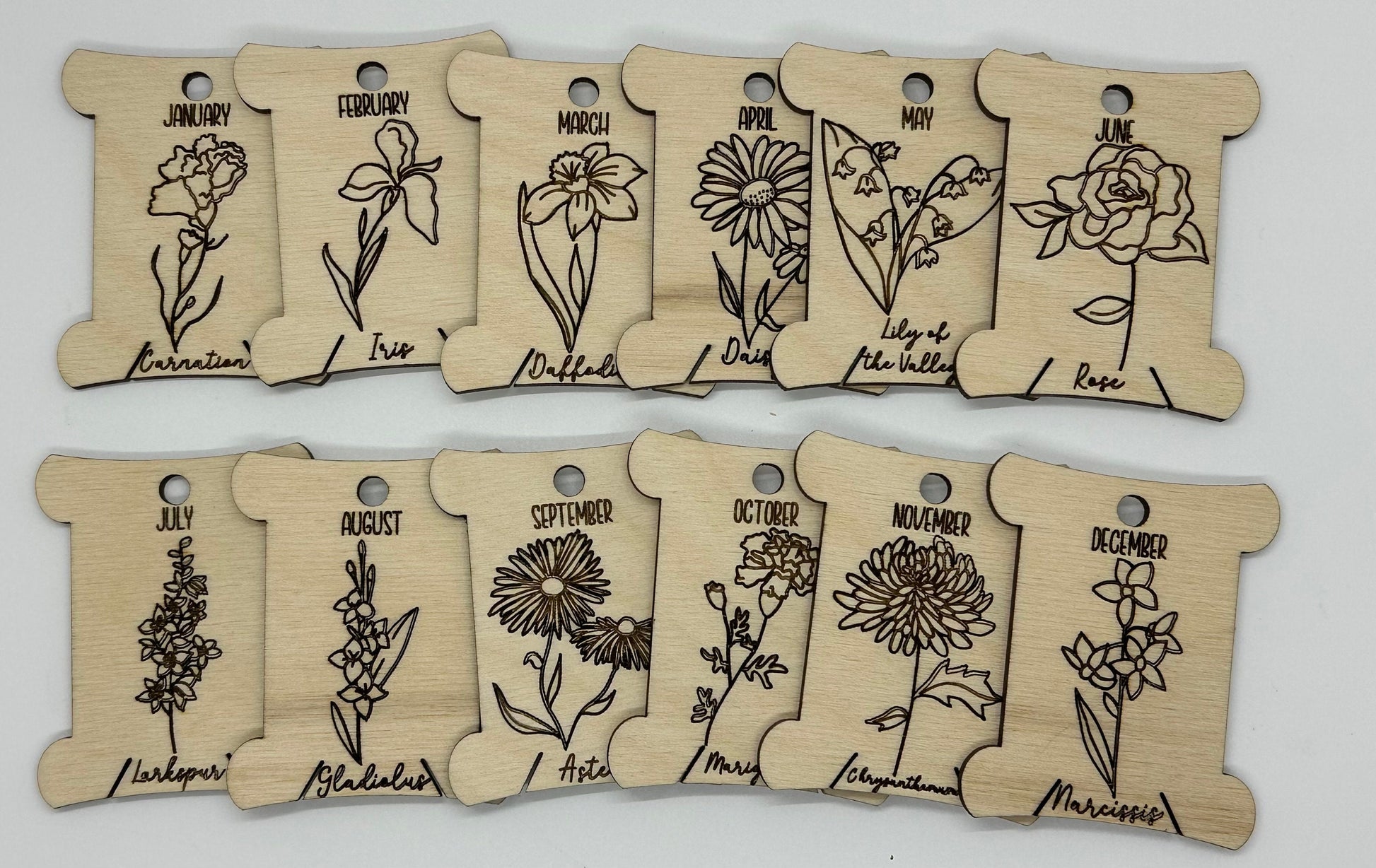 Wooden bobbins with floral designs and months' names on a white background