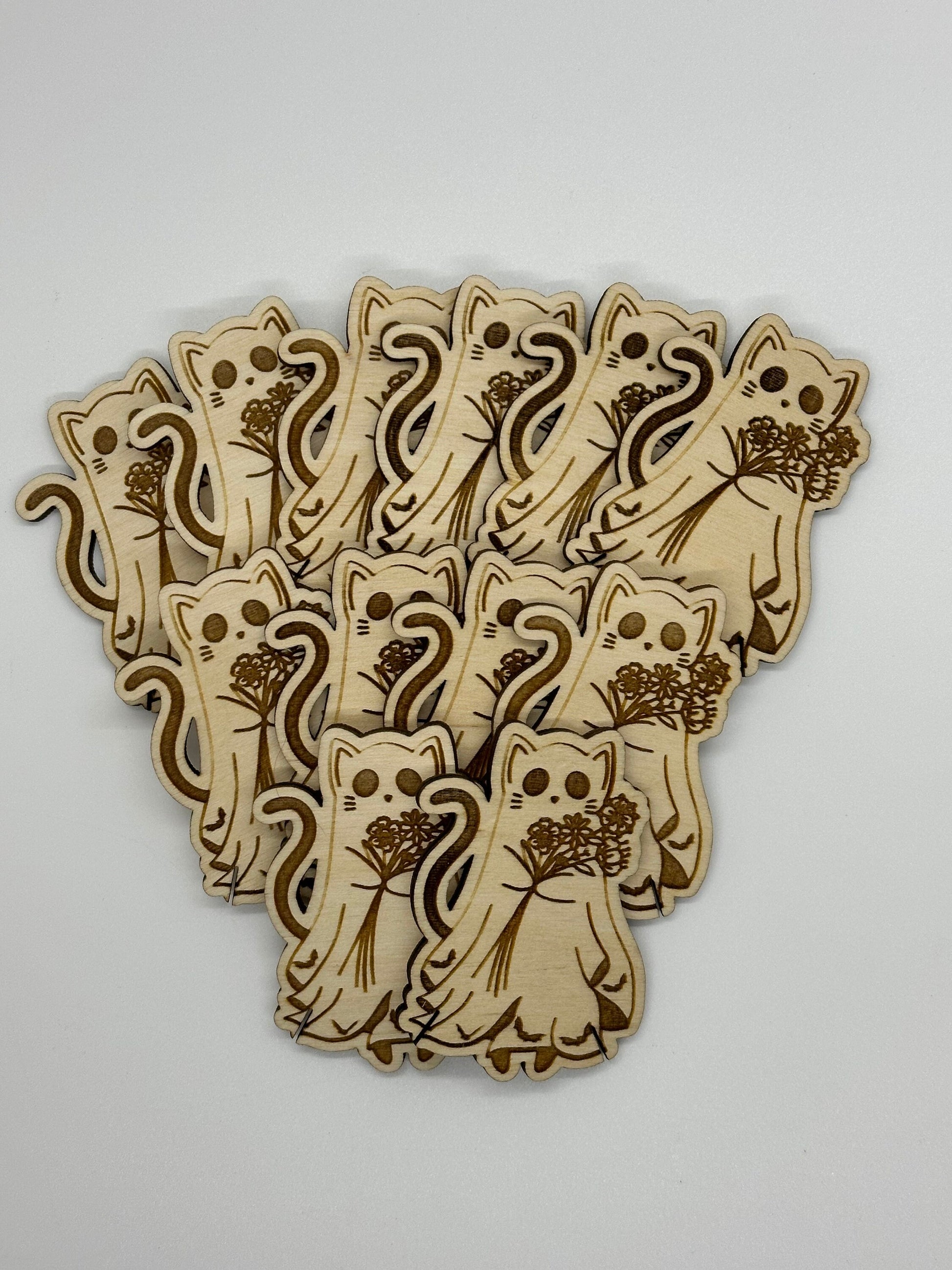 Set of wooden cat-shaped bobbins with floral designs on a light gray background
