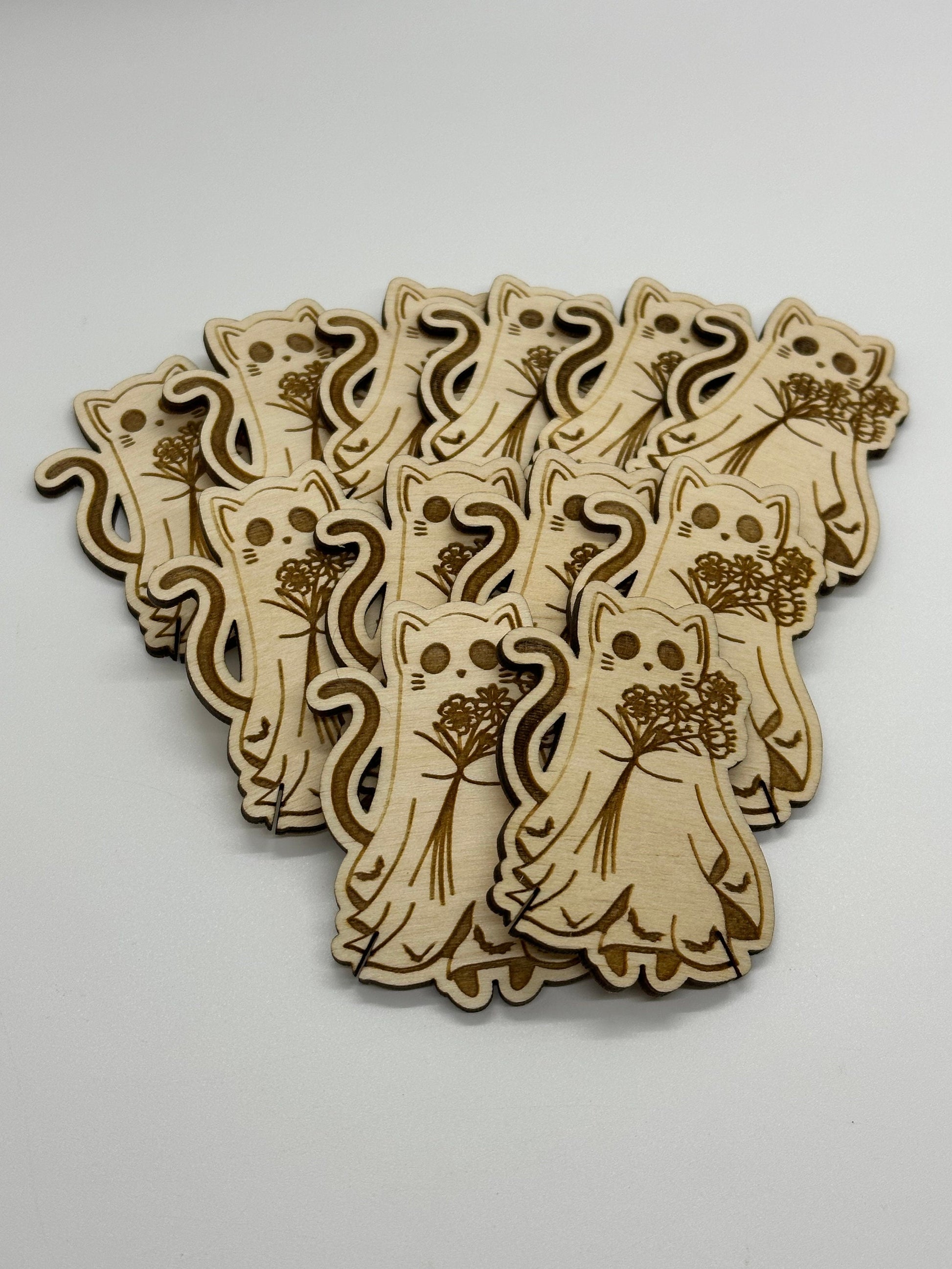 Wooden cat-shaped bobbins with floral bouquets on a white background