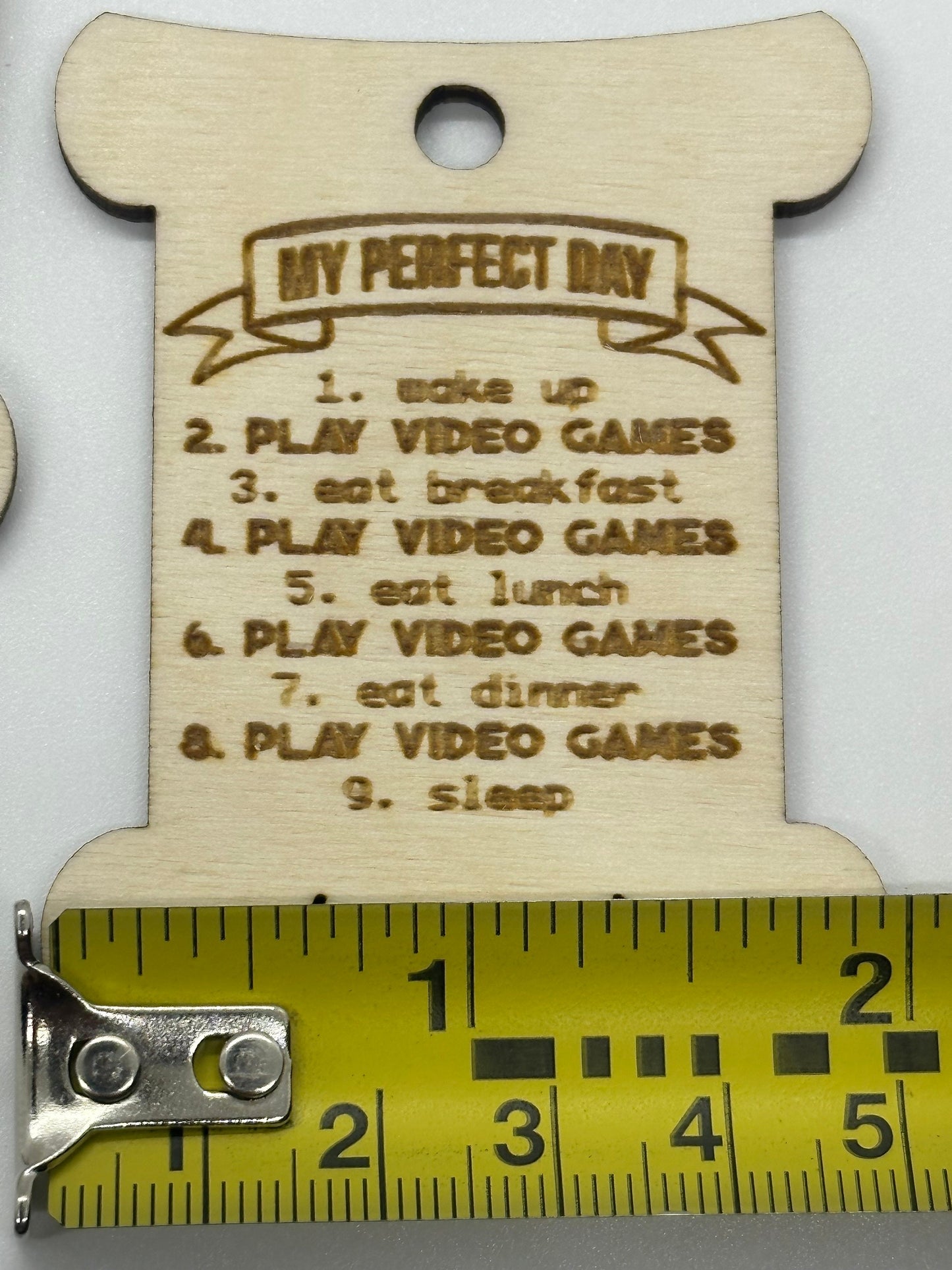 Wooden bobbin with 'My Perfect Day' list and a tape measure for scale on a white background
