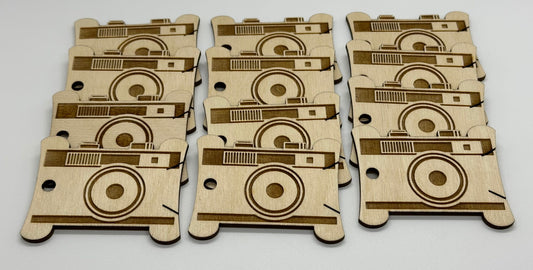 Set of laser-cut wooden bobbins with camera design on a white background