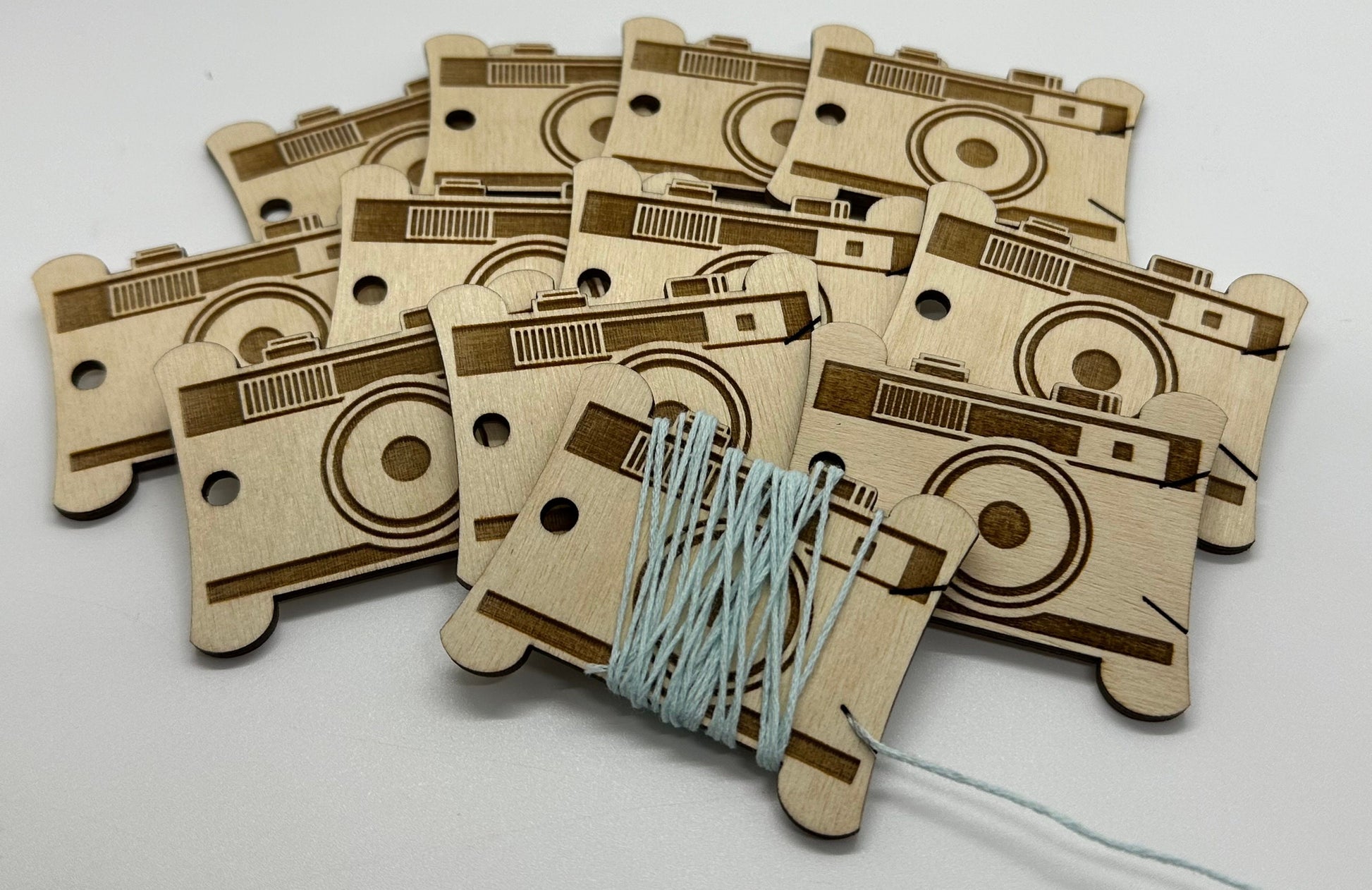 Wooden bobbins shaped like camels with string attached on a white background
