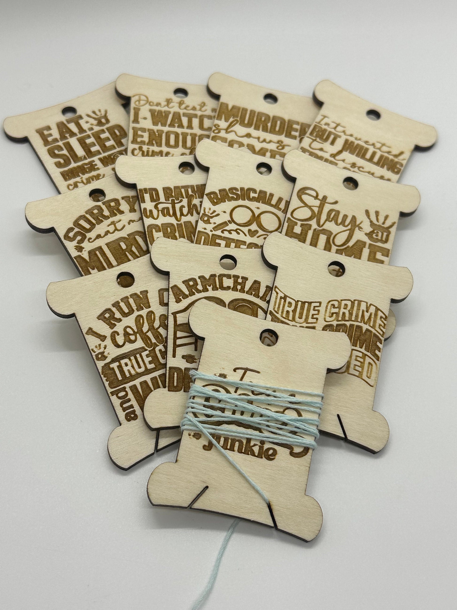 Wooden bobbins with humorous text designs on a white background