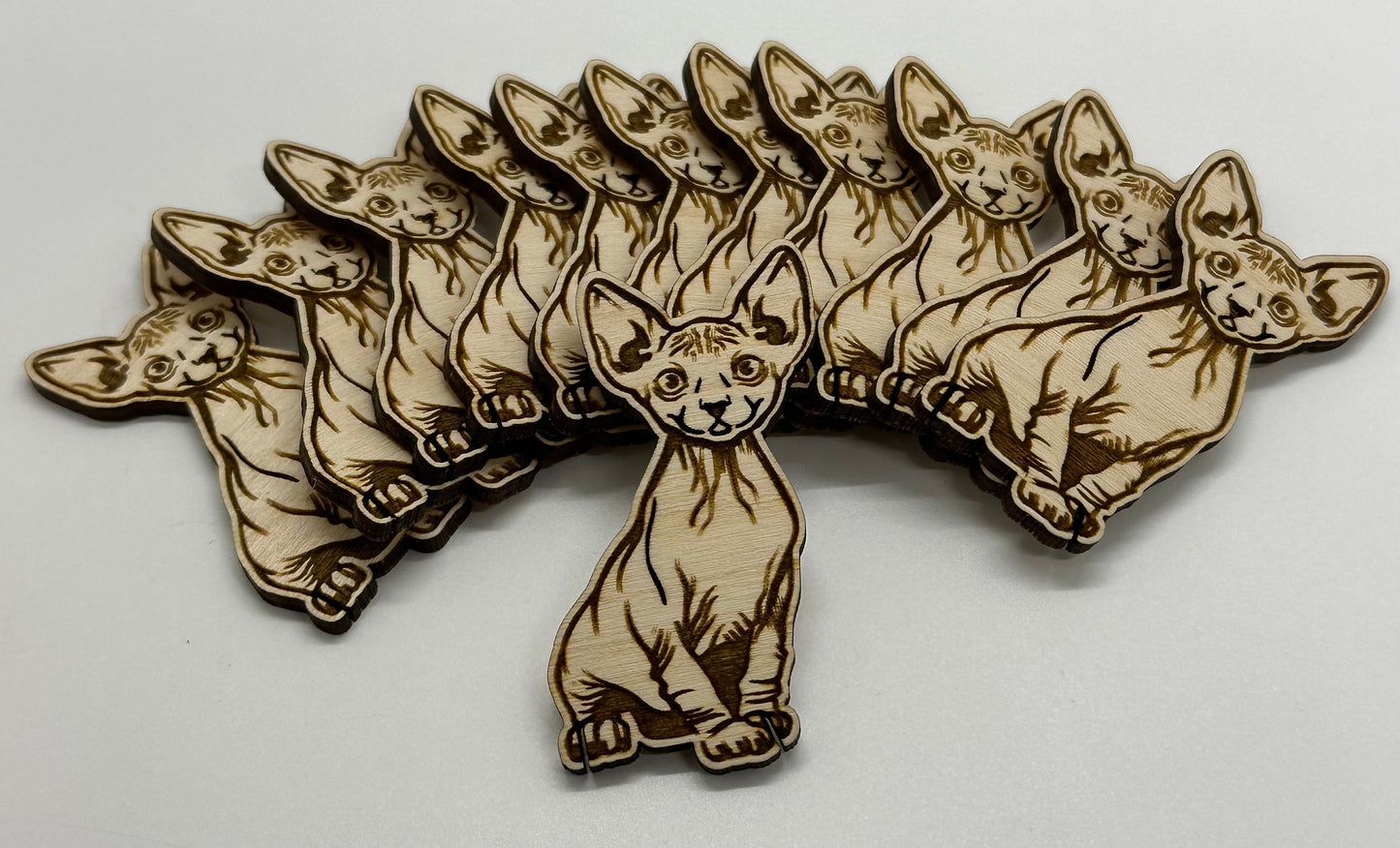 Wooden cat-shaped bobbins arranged in a fan-like pattern on a white background