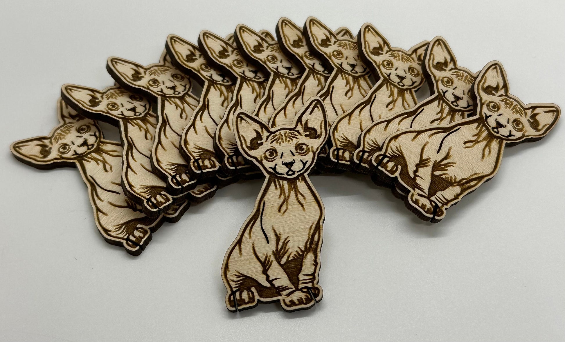 Wooden cat-shaped bobbins arranged in a fan-like pattern on a white background