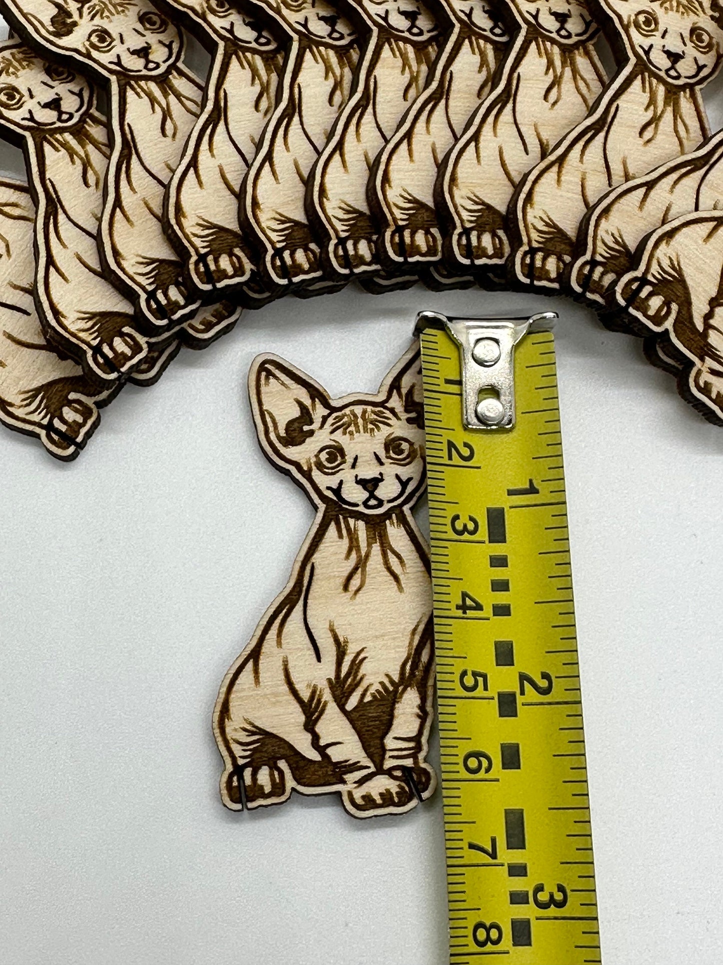 Wooden cat-shaped cutout with a ruler for scale on a white background
