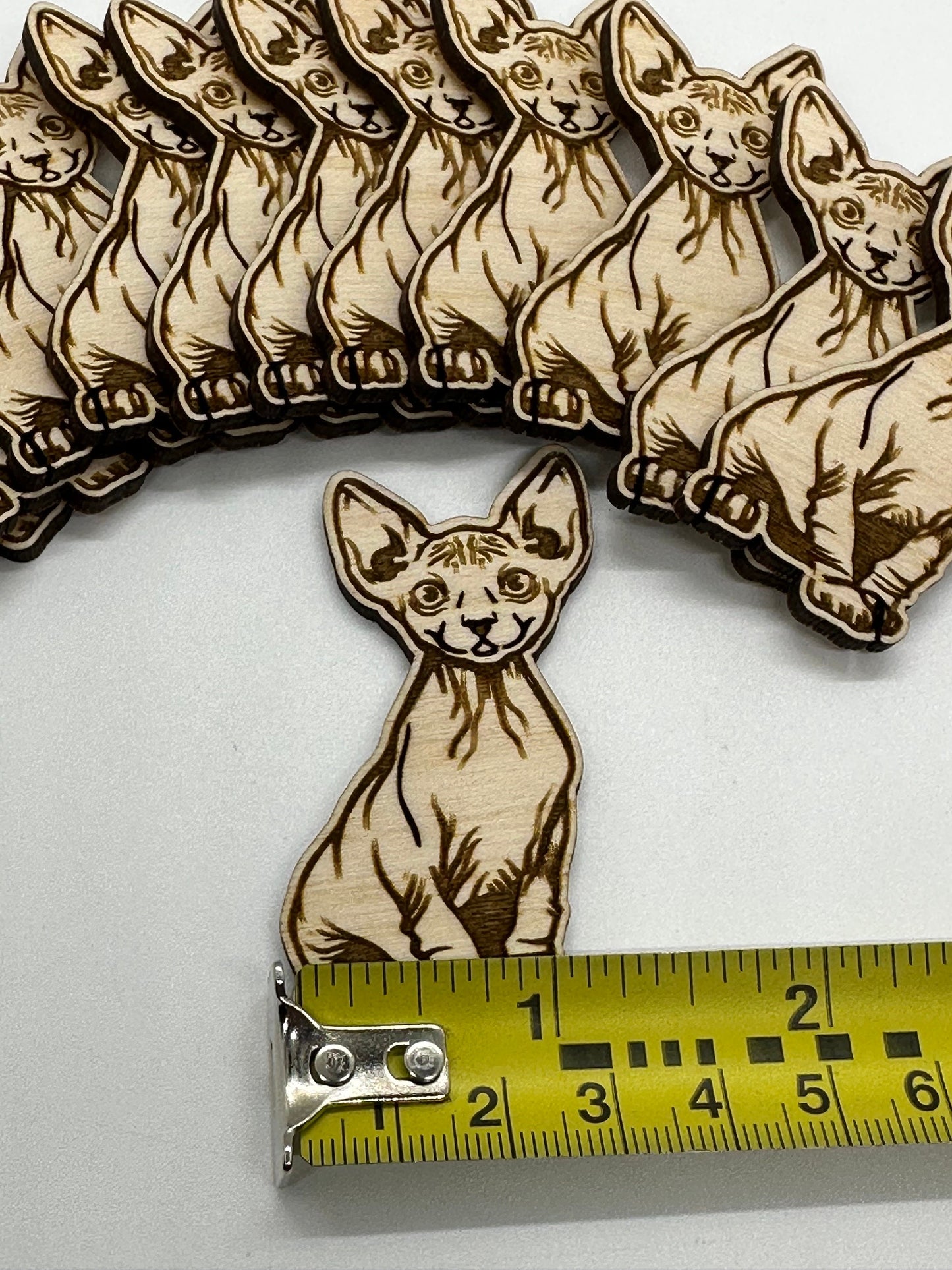 Wooden Sphynx cat cutouts with a ruler for scale on a white background