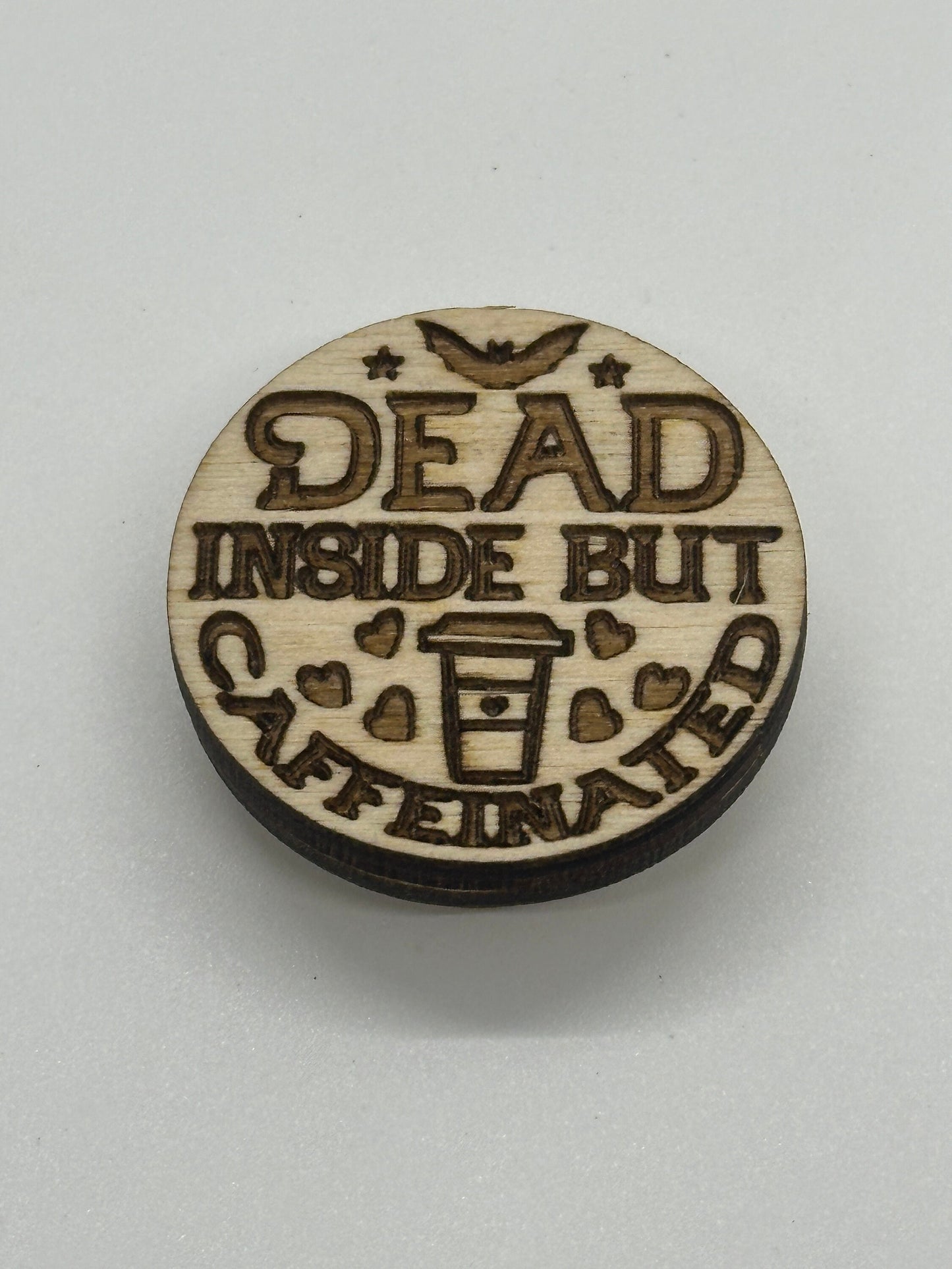 Wooden round sign with 'Dead inside but caffeinated' text on a white background