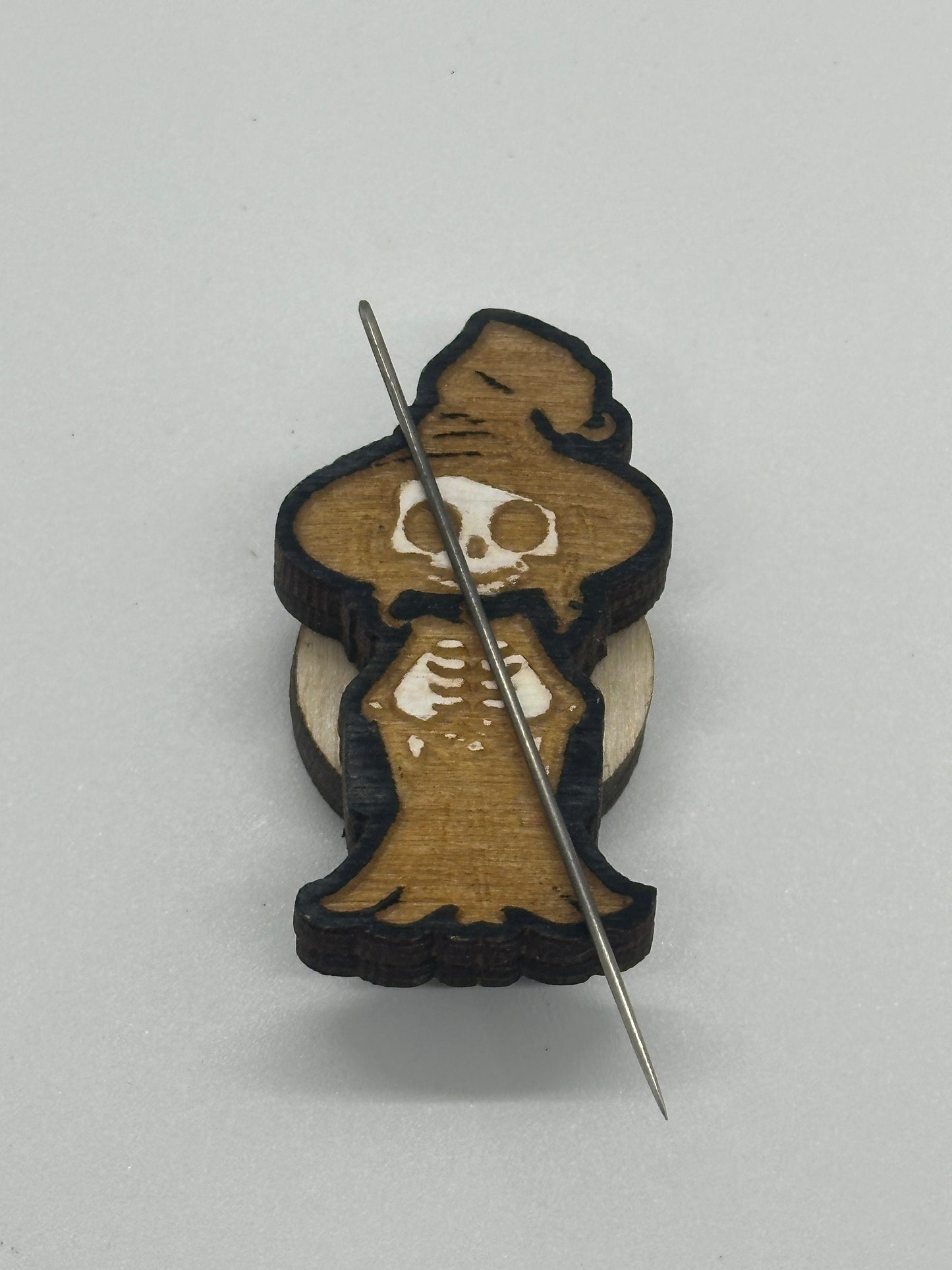Wooden minder with skeleton design and a needle on a white background