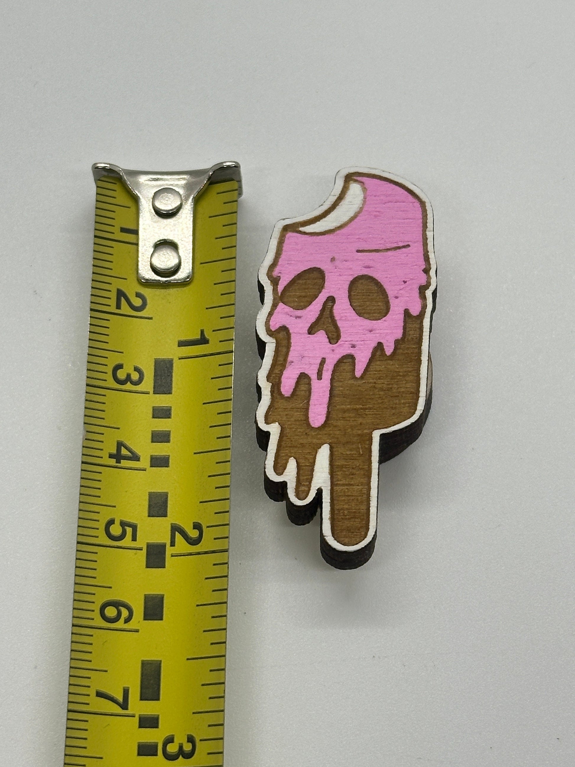 Ice cream cone-shaped object with pink top next to a ruler on a gray background