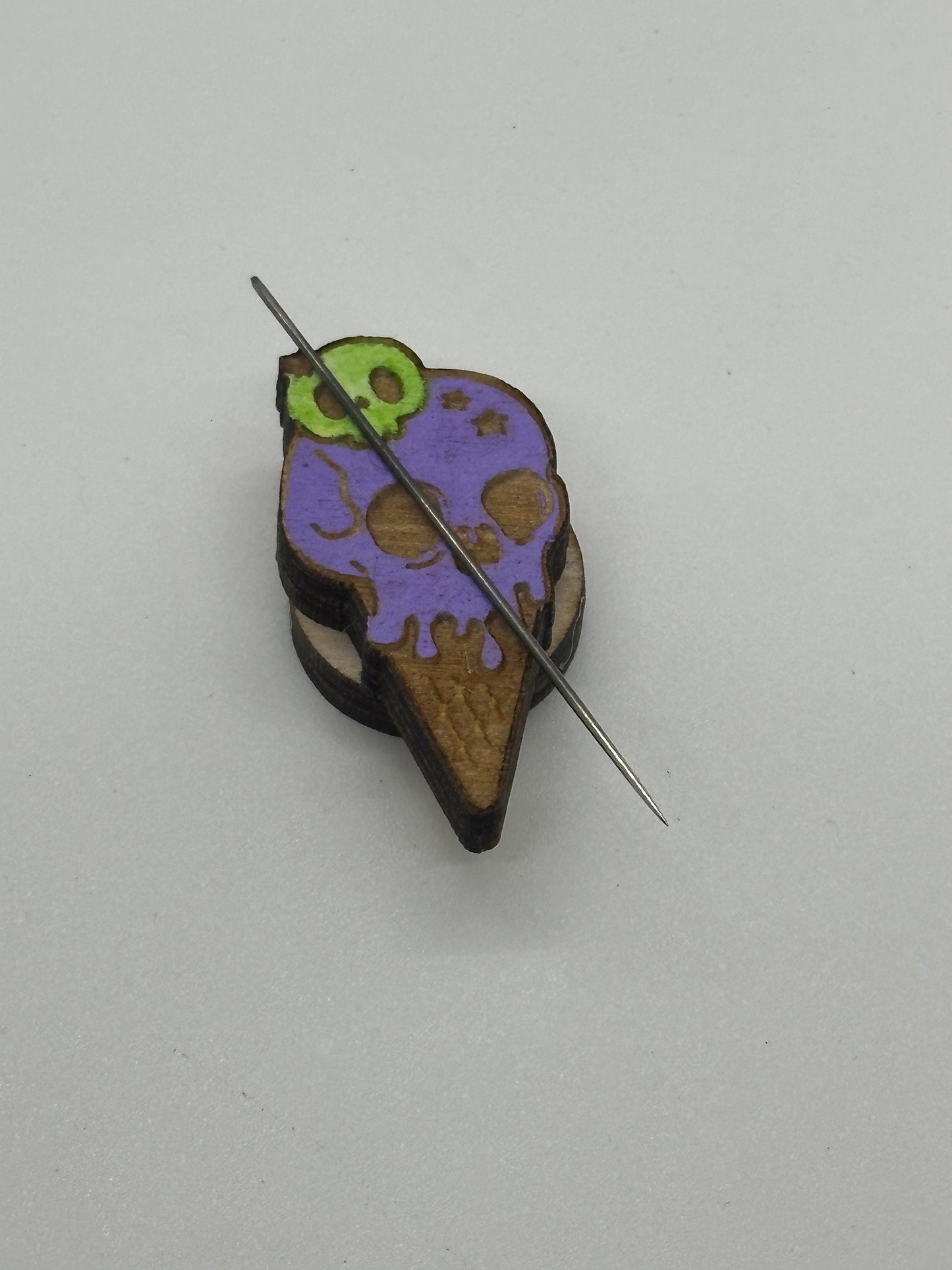 Colorful ice cream cone-shaped brooch with a needle on a light gray background