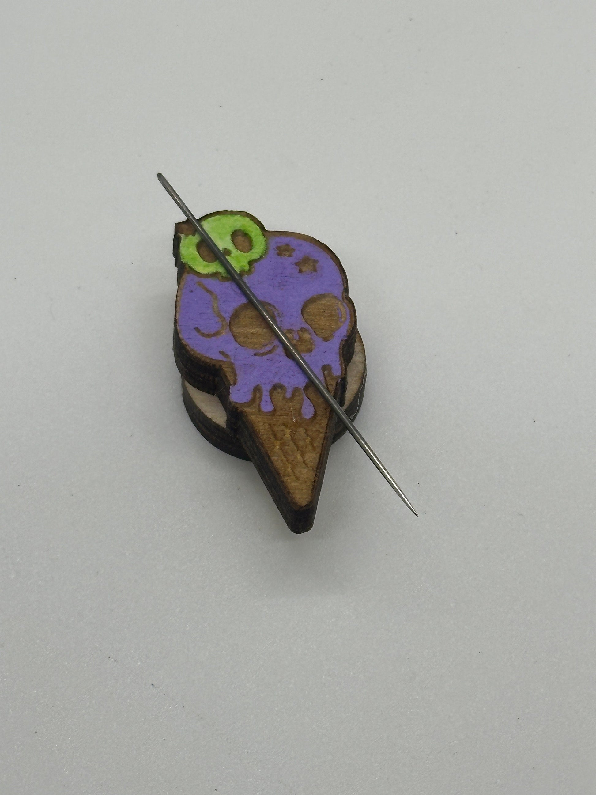 Colorful ice cream cone-shaped brooch with a needle on a light gray background