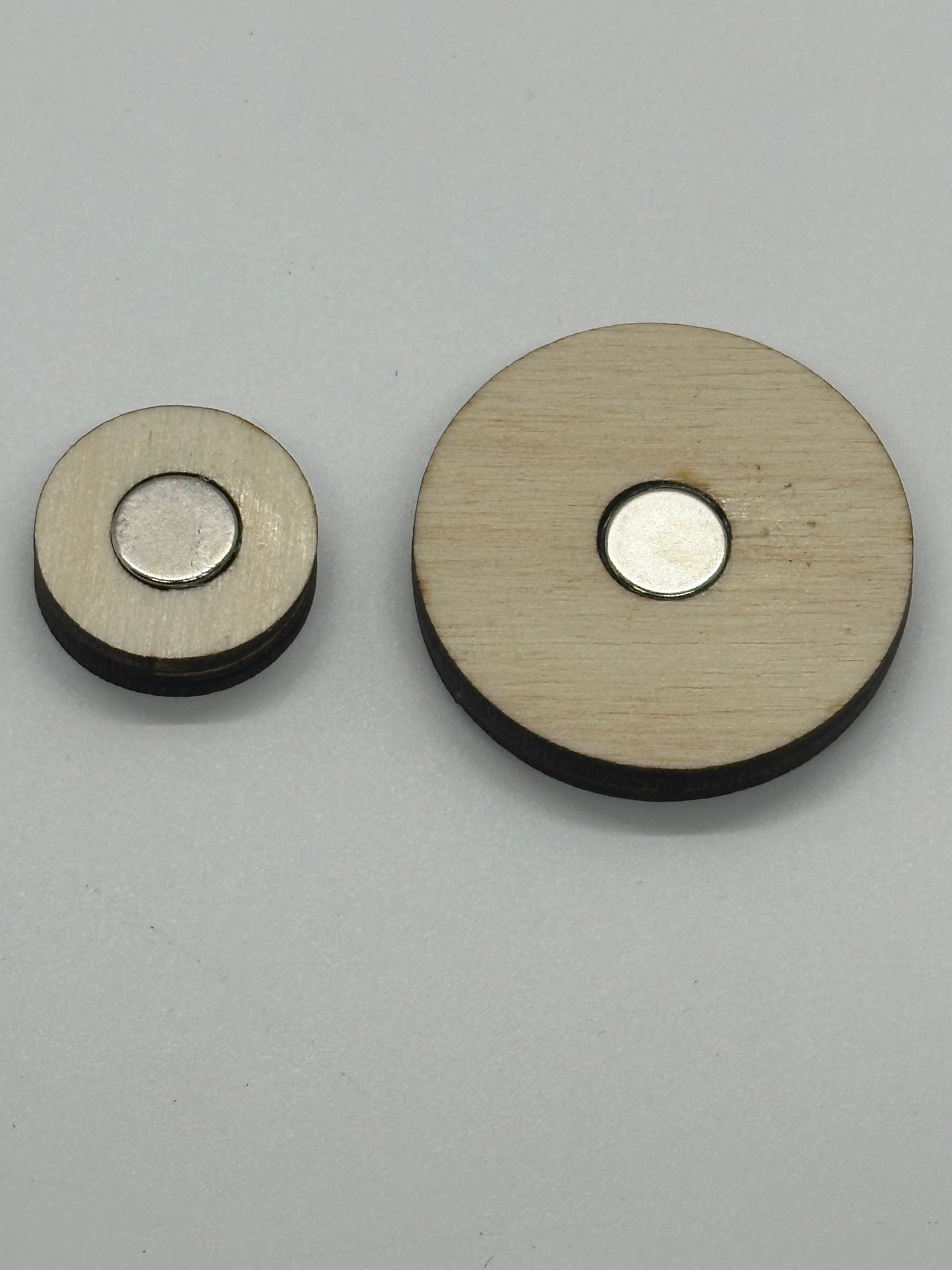 Two round metallic objects with one being larger and the other smaller, on a gray background.