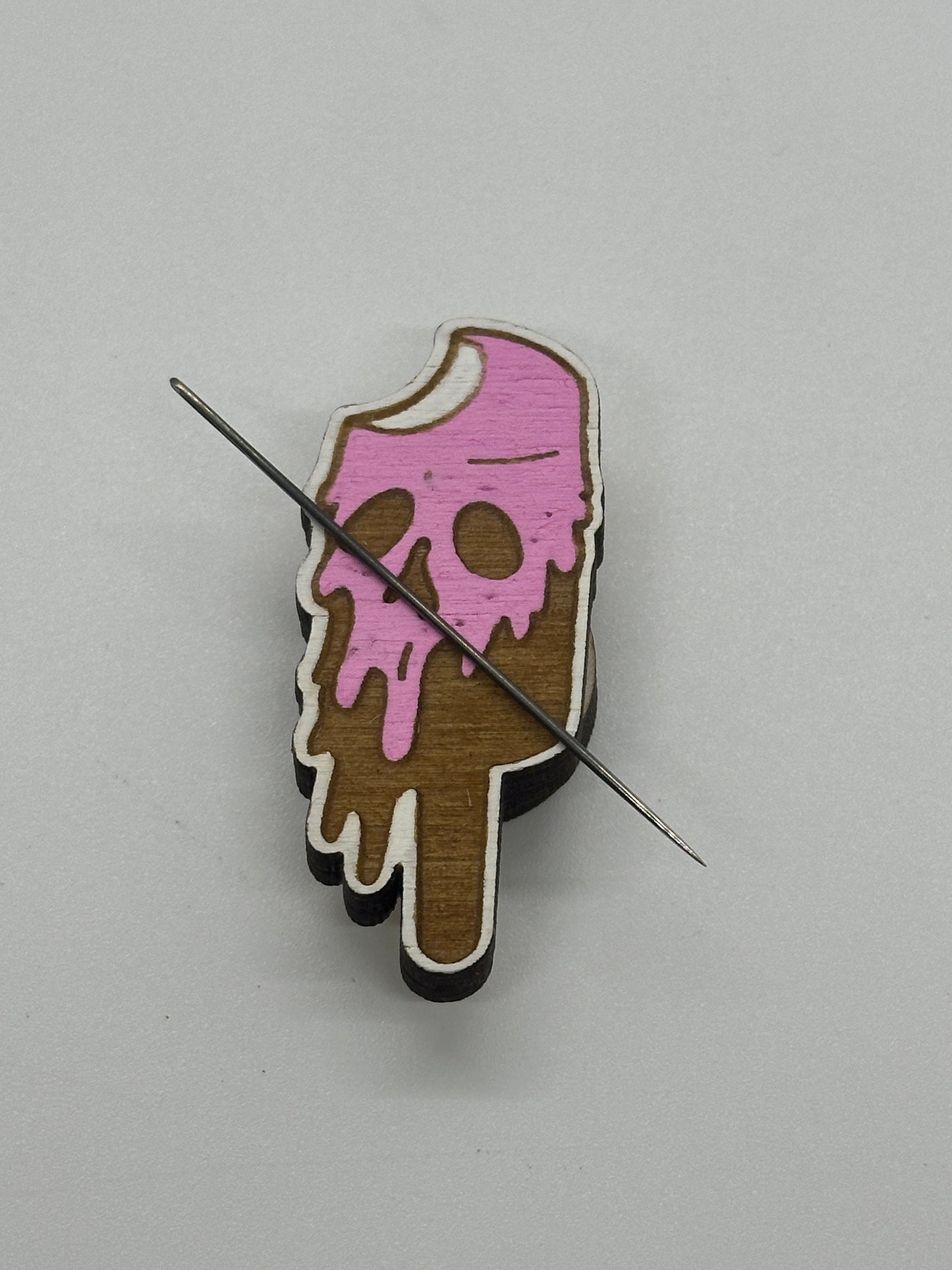 Wooden ice cream cone with pink melting top on a gray background