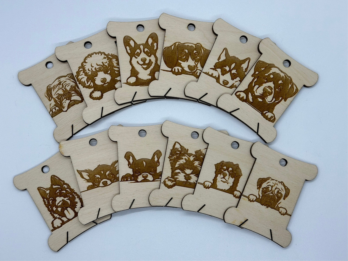 Set of wooden bobbins with engraved dog illustrations on a light blue background