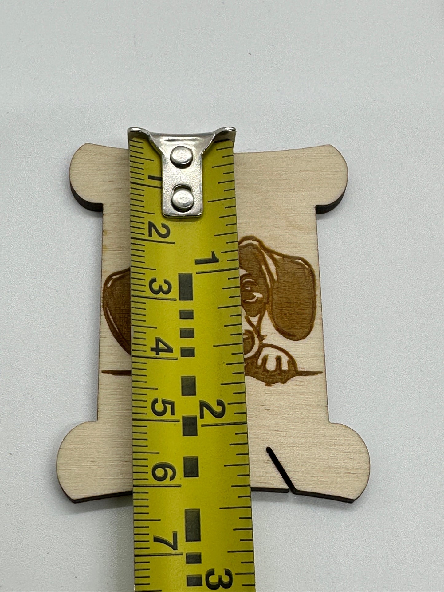 Wooden bobbin  ruler with measurement markings on a light gray background