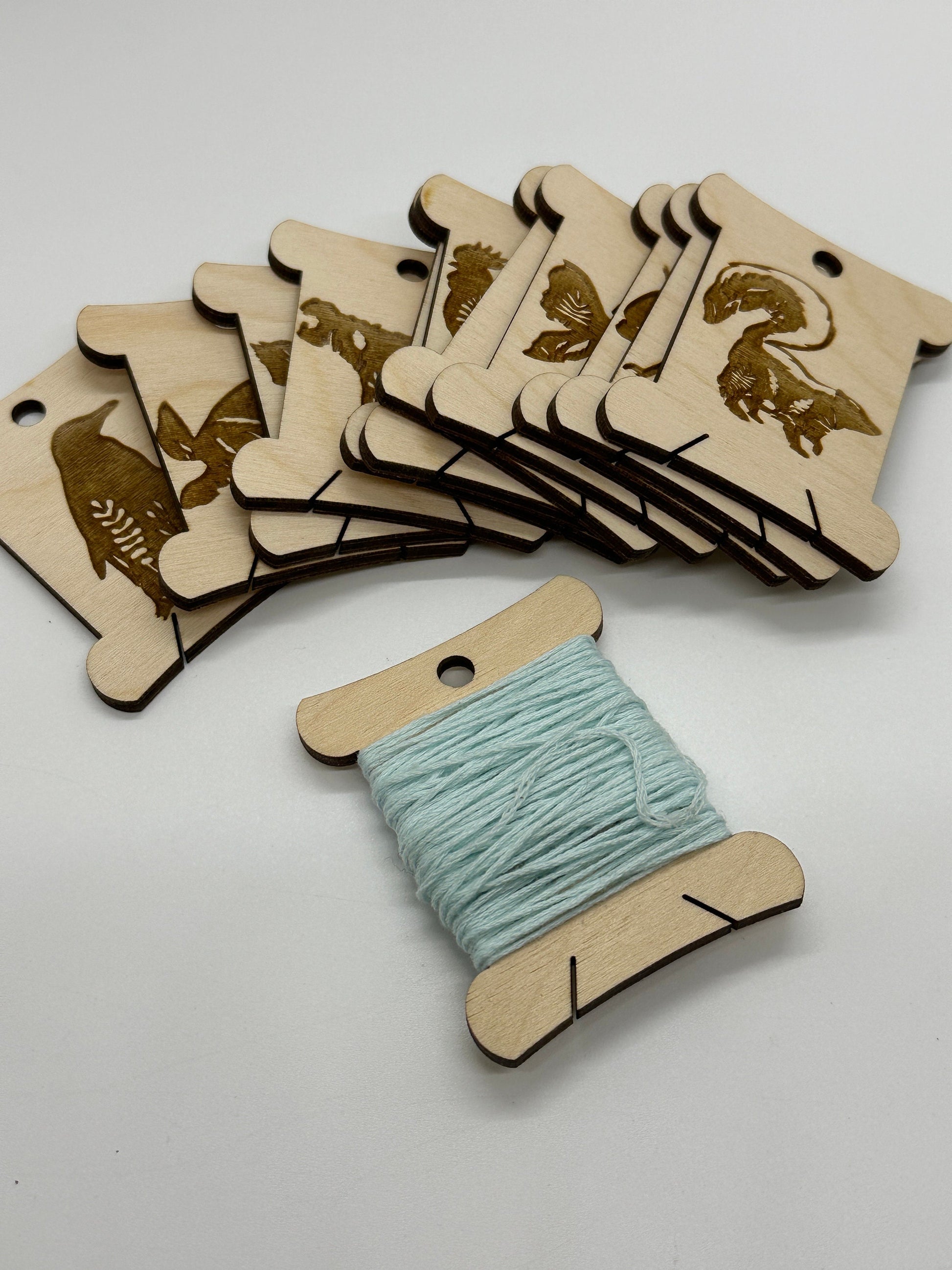 Wooden thread spools with animal designs on a white background
