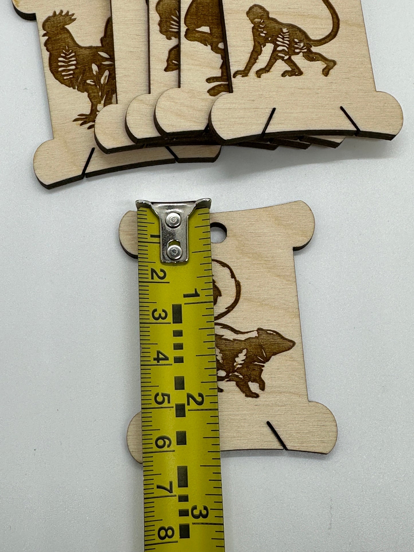 Wooden animal-shaped cutouts with a measuring tape for scale on a white background