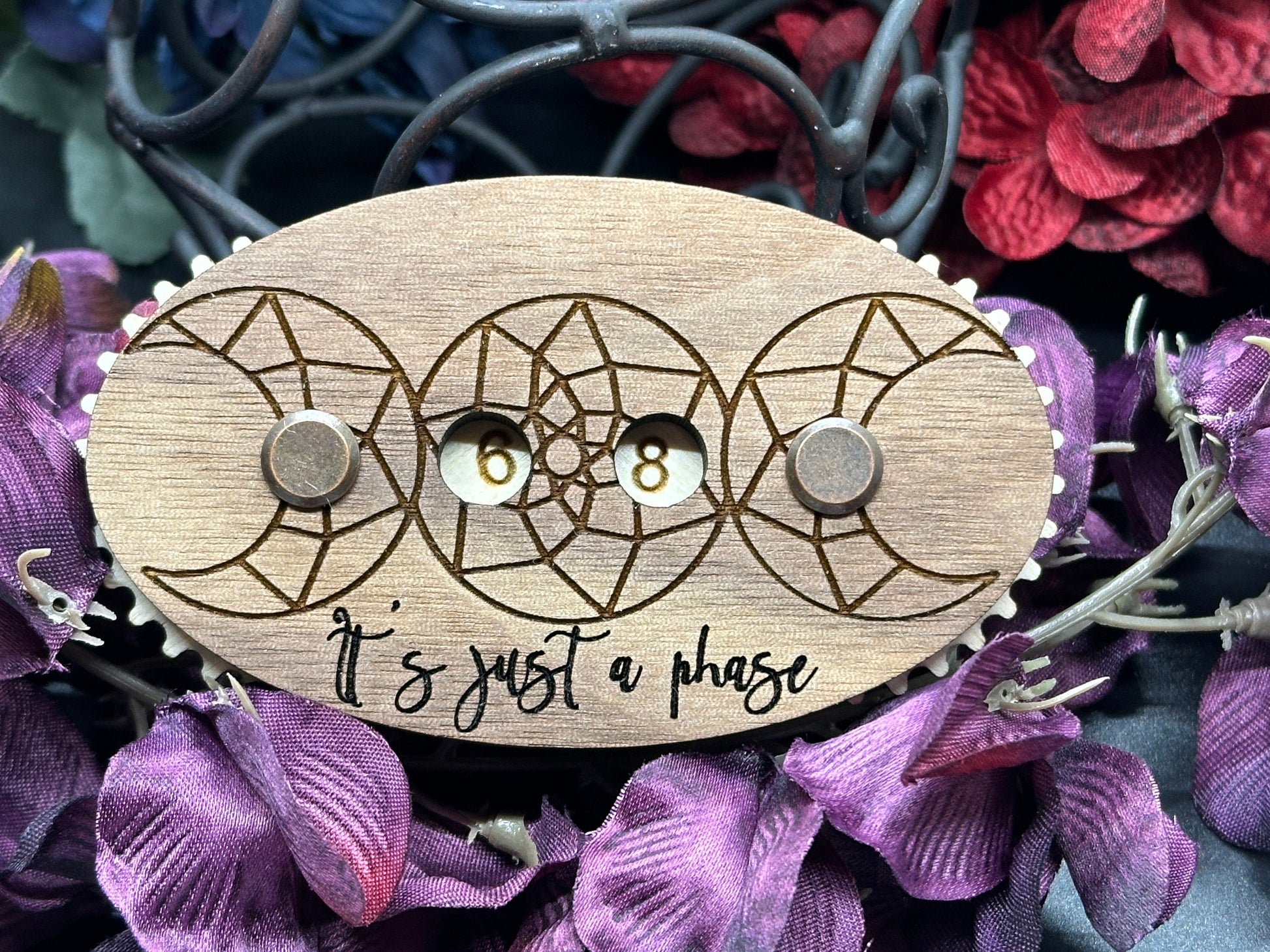 Wooden counter with moon design and 'It's just a phase' text on a floral background