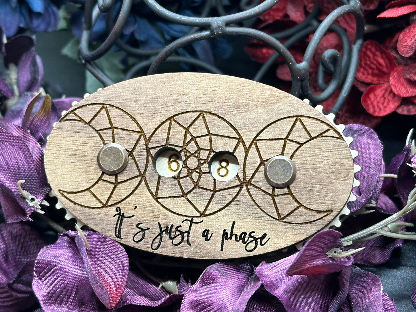 Wooden counter with moon design and 'It's just a phase' text on purple flowers