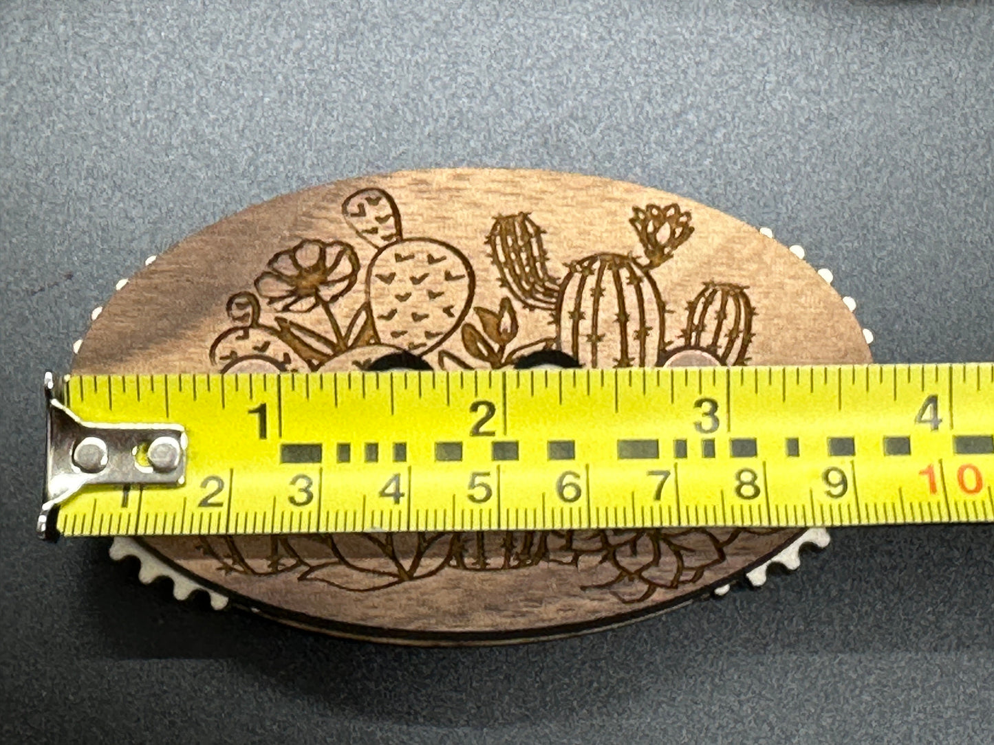 Wooden counter with cactus design and measurement tape for scale on a gray background