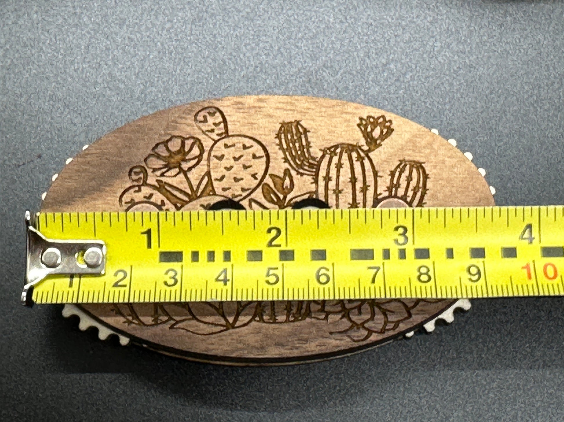 Wooden counter with cactus design and measurement tape for scale on a gray background