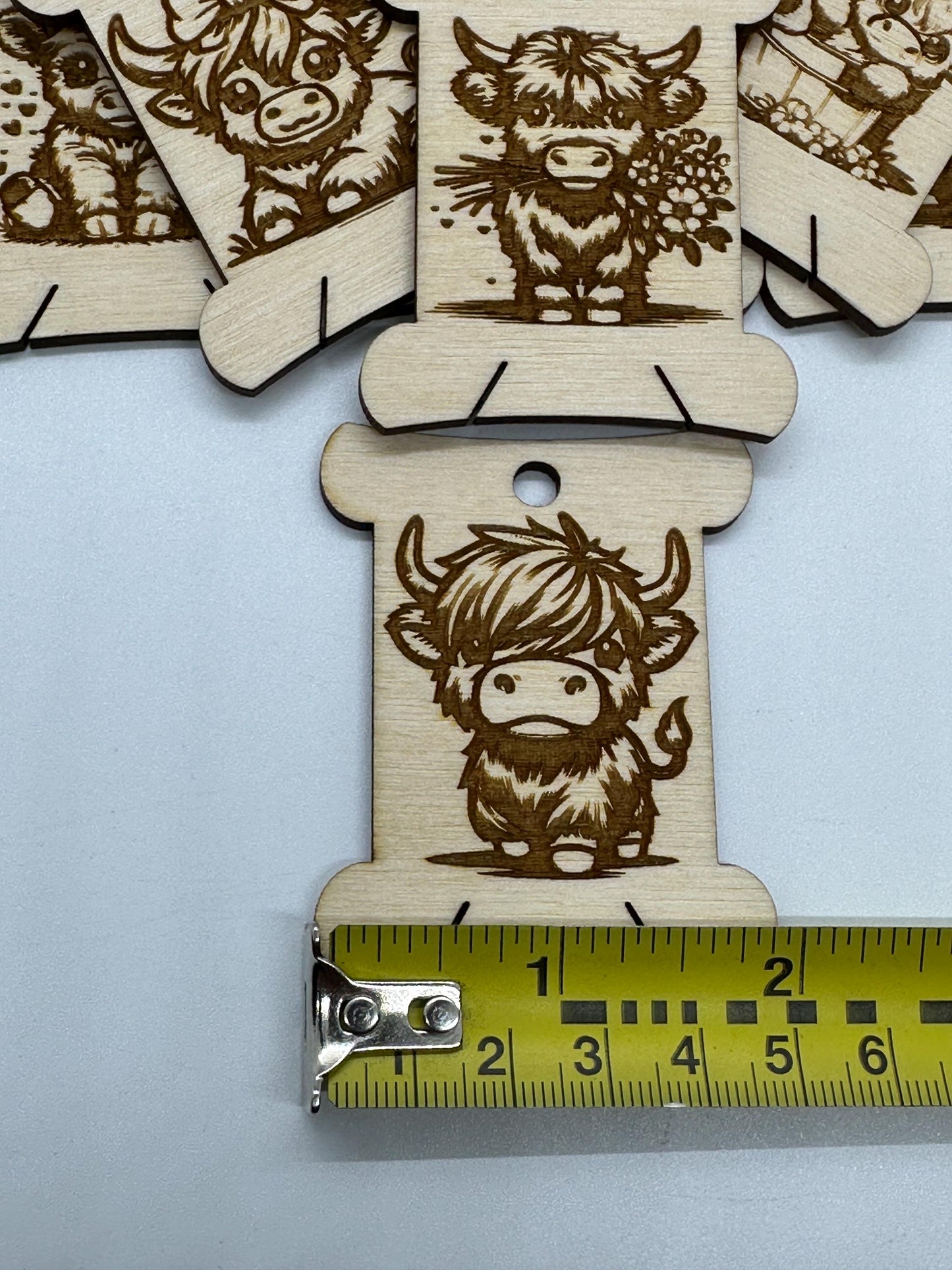 Wooden cutouts with engraved animal designs on a light blue background, with a ruler for scale.